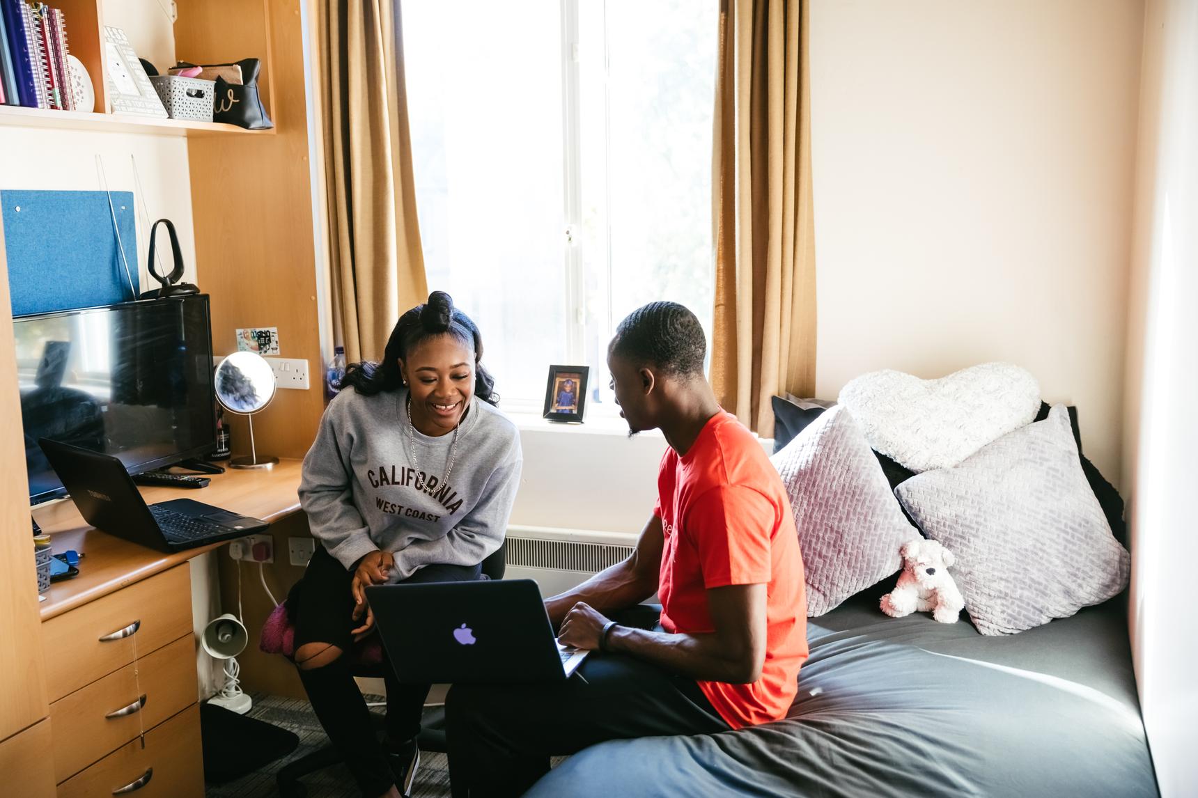 two students sit in bedroom studying together