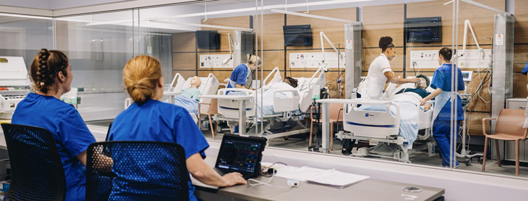 Two nurses observing training practices in a training hospital ward