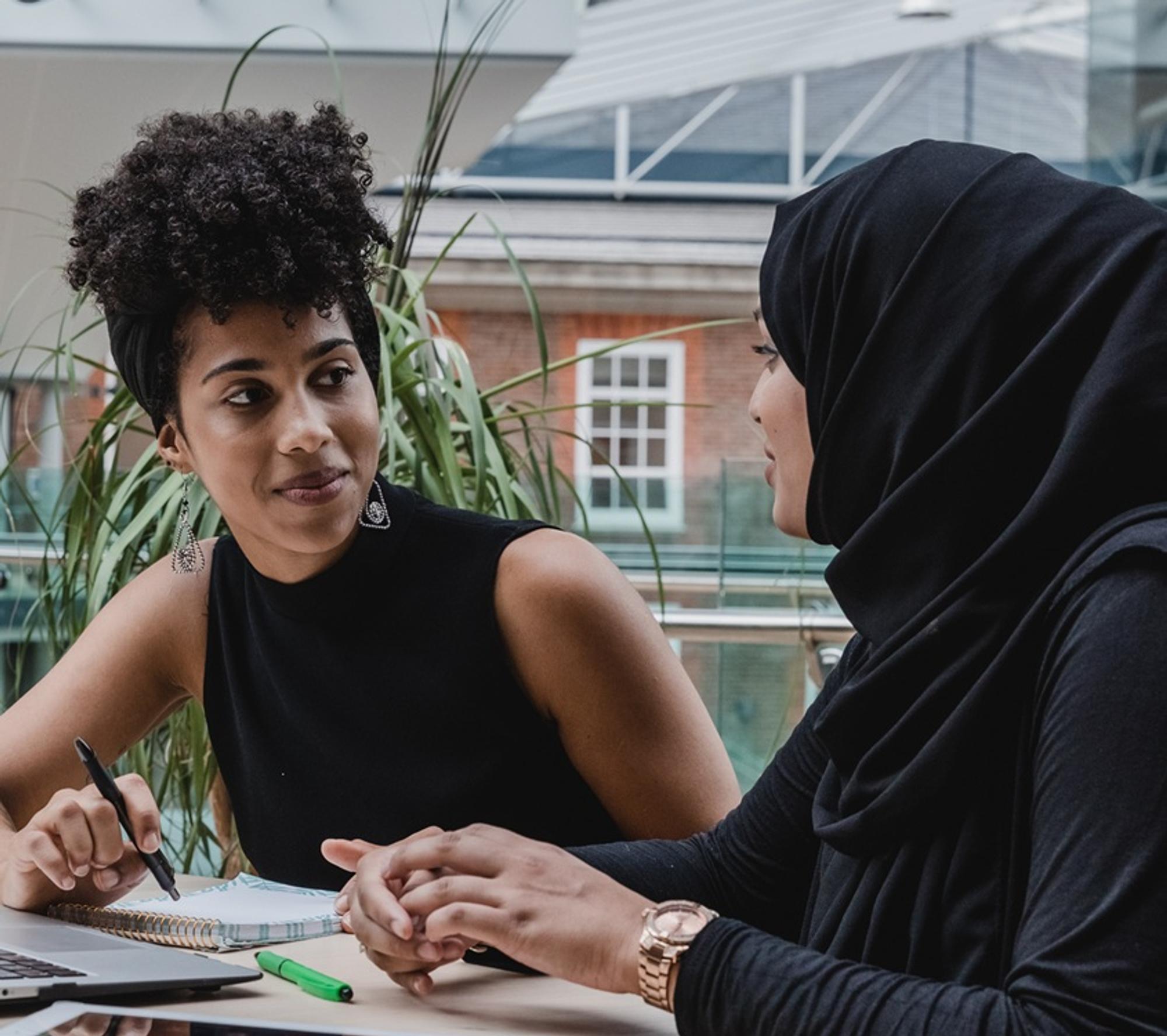 Two women sitting at a table and speaking to each other