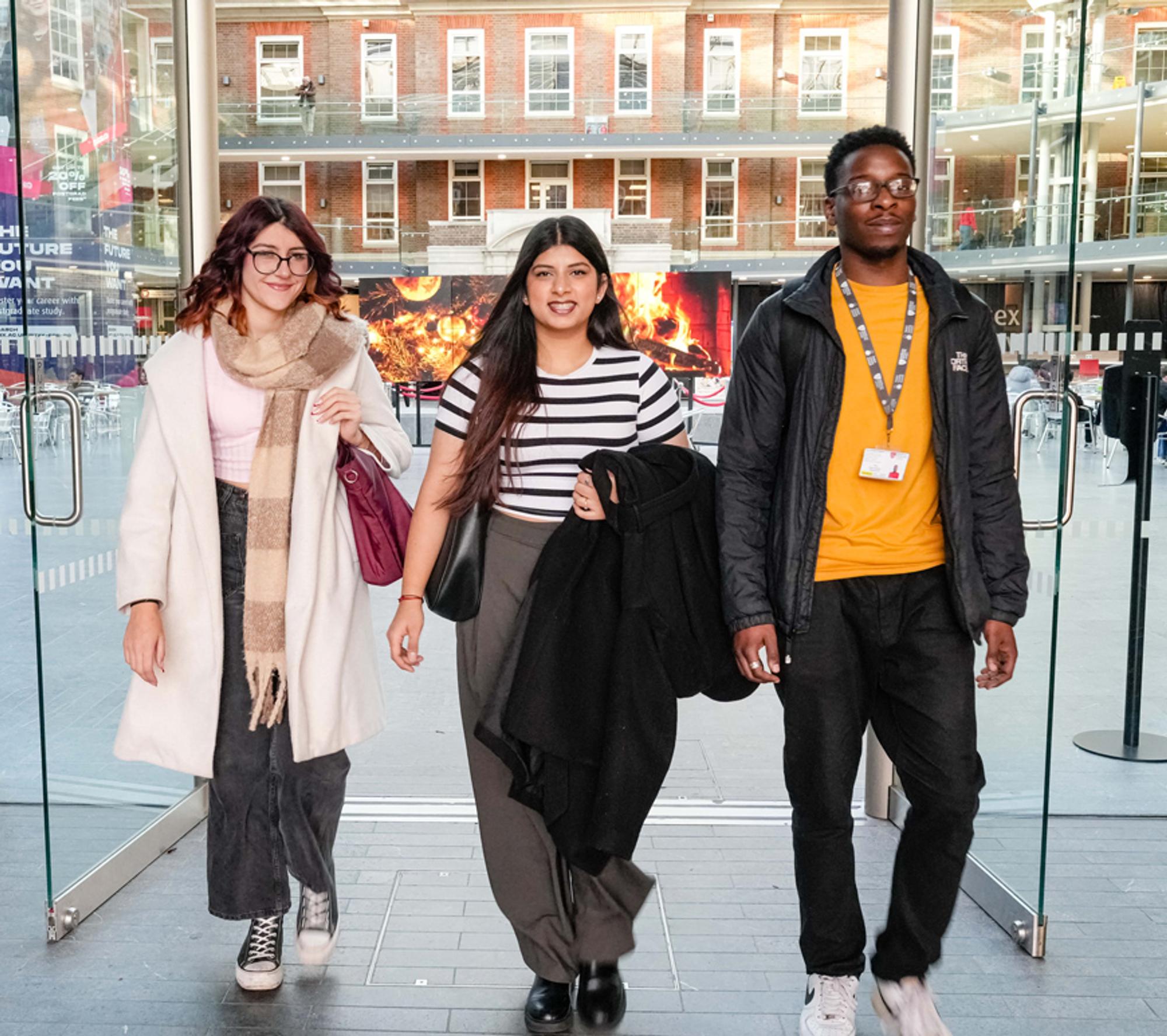 three students walking through a door on the 91��ɫ University campus