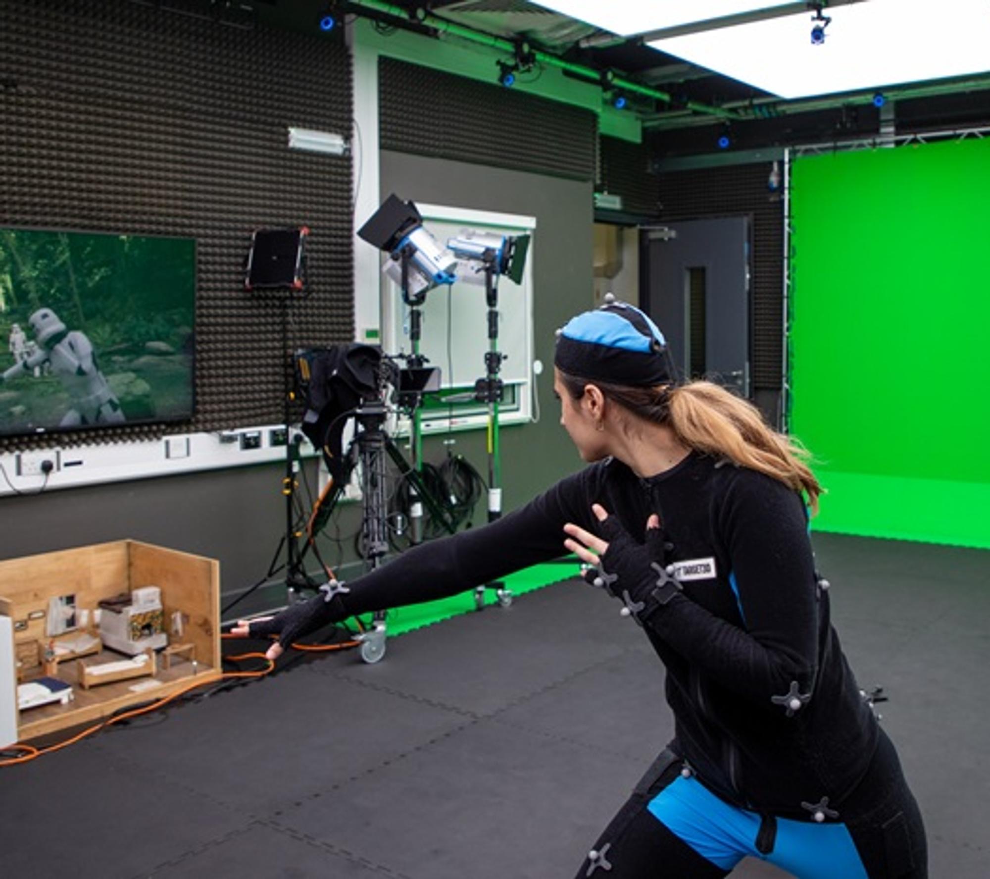 A person in a motion capture suit pushing their fist forward, with an animated soldier on a screen emulating the action