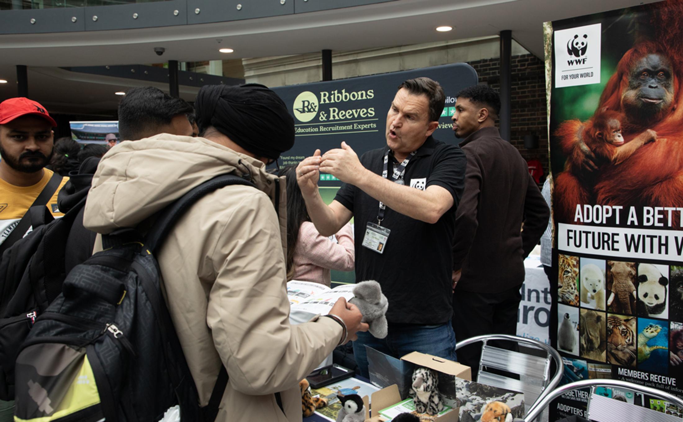 A man is describing something in an animated way to a younger person at an event