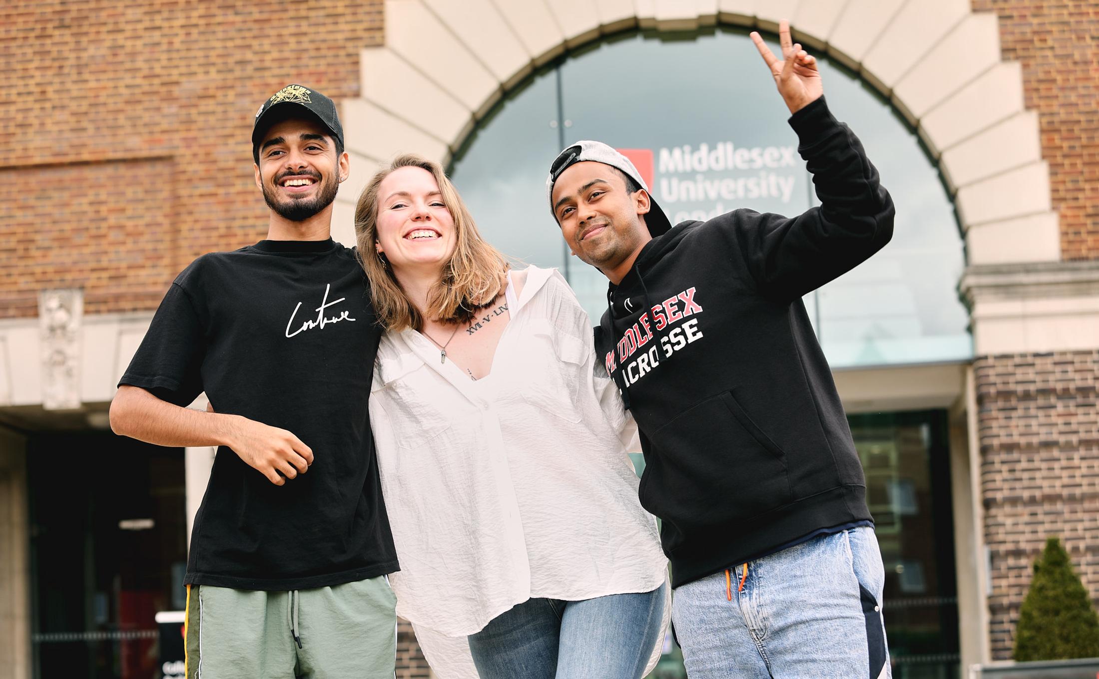 Three students stood together outside on campus