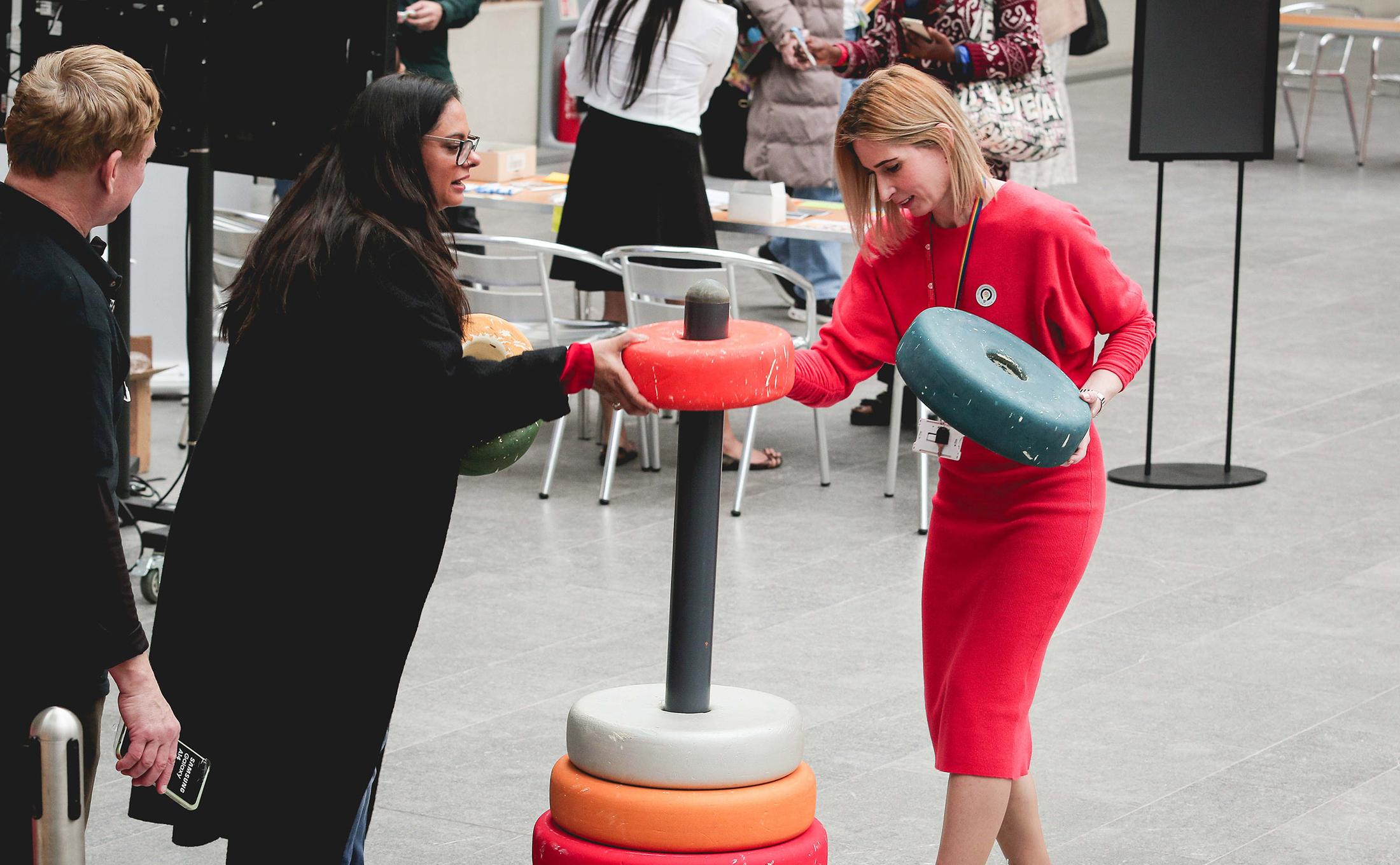 two people playing game with giant coloured hoops stacked on a pole