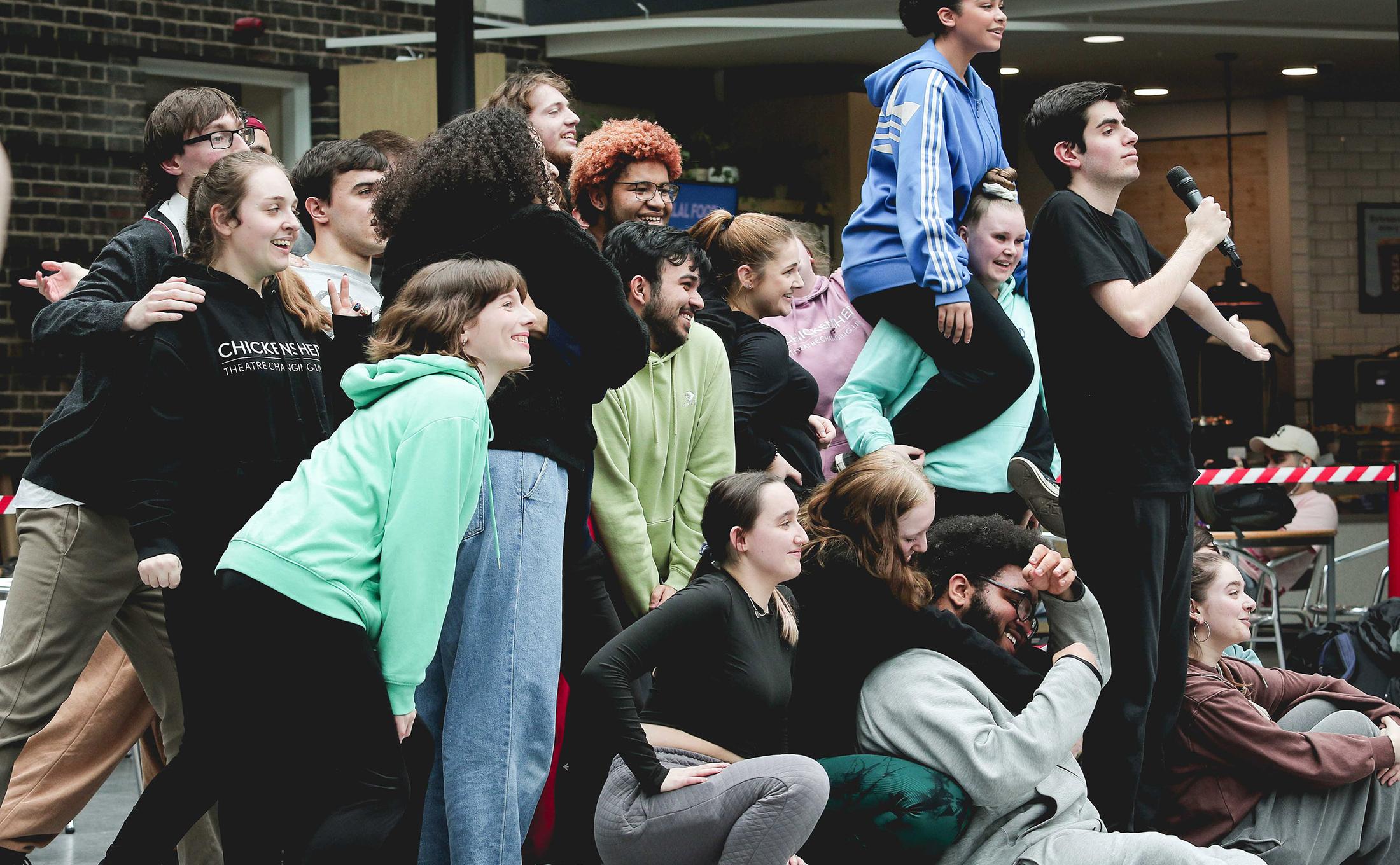 Large group of people posing behind performer with microphone