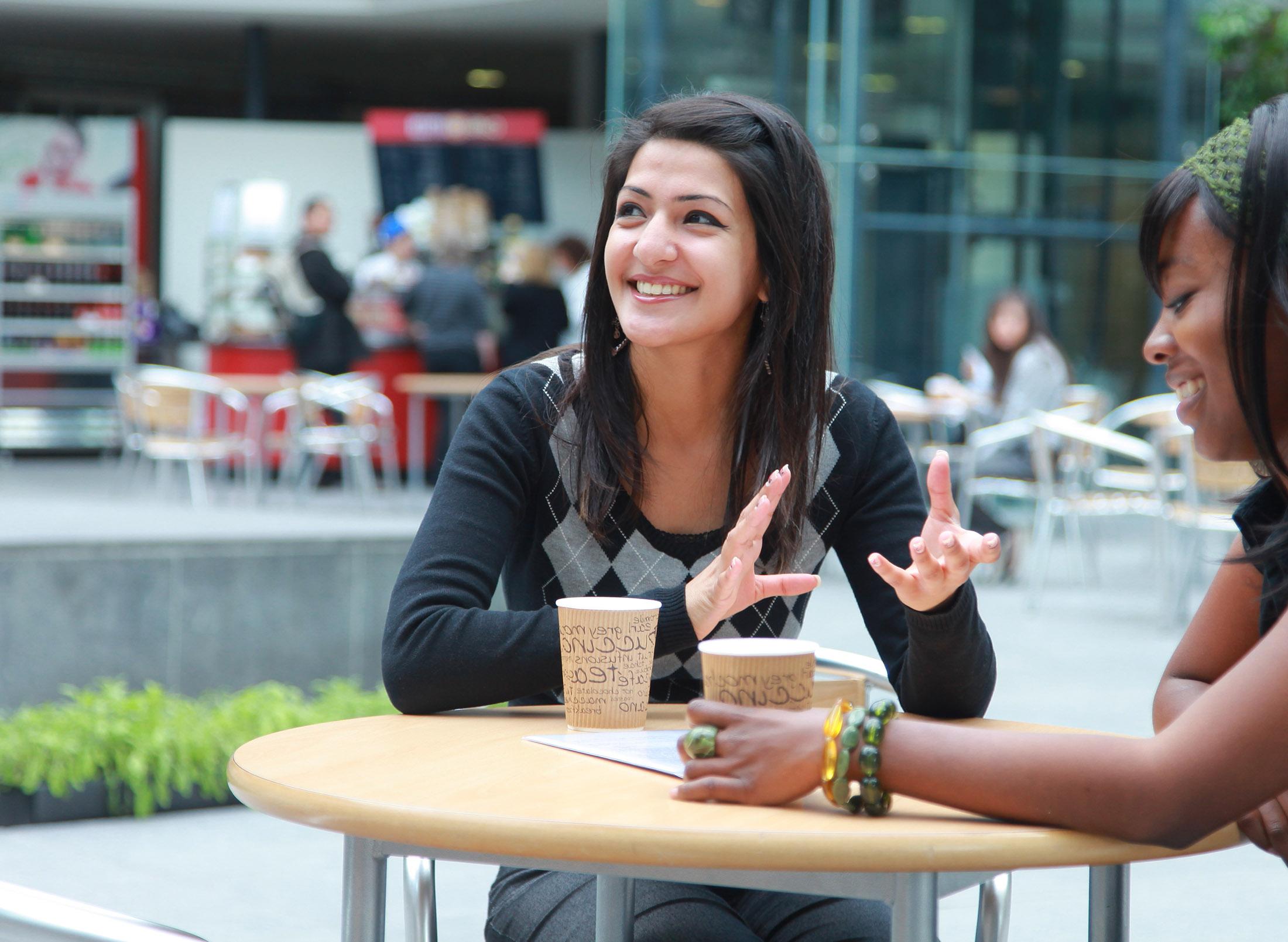 two happy students sitting in quad