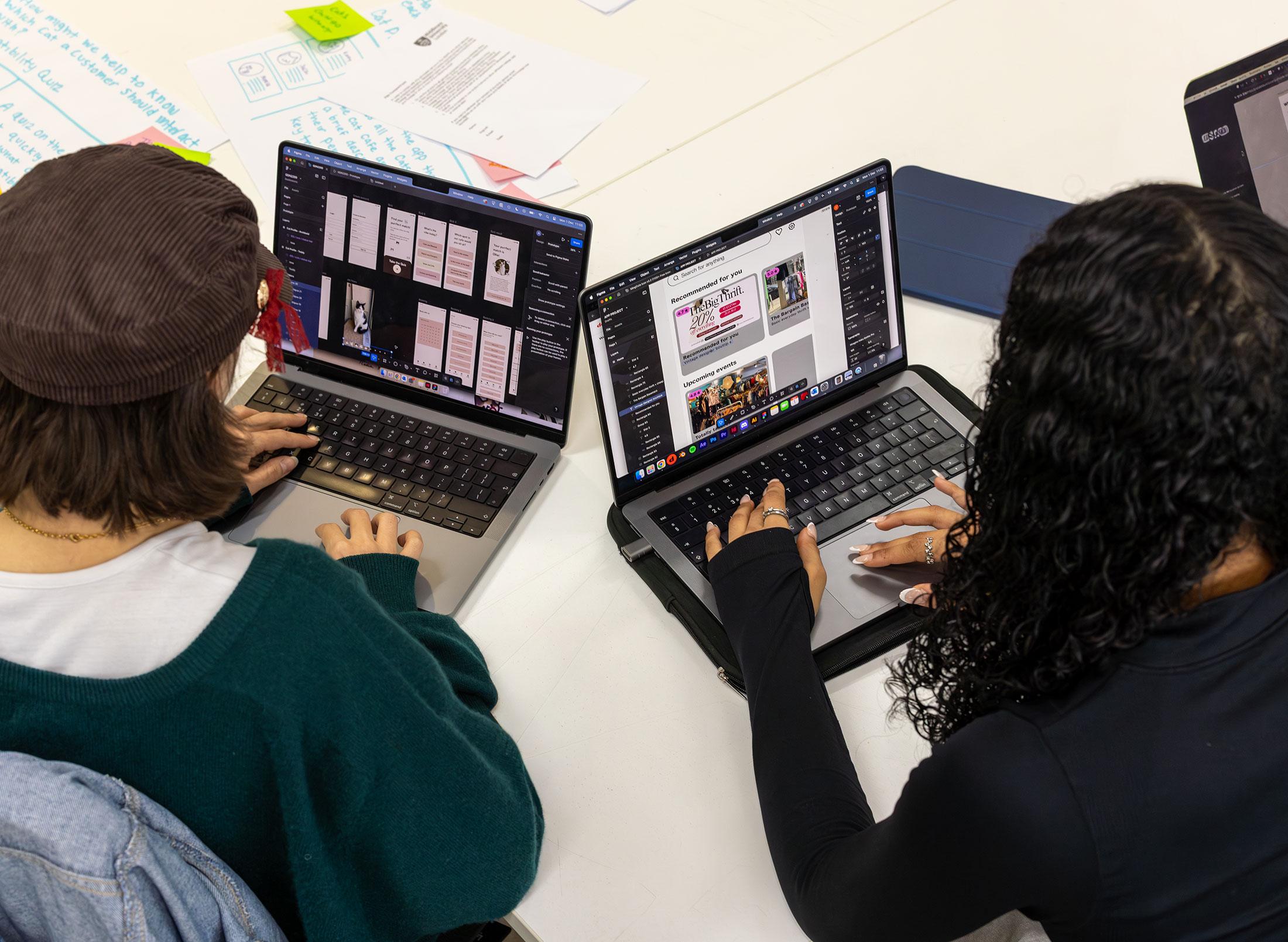 Two students creating content on their laptops