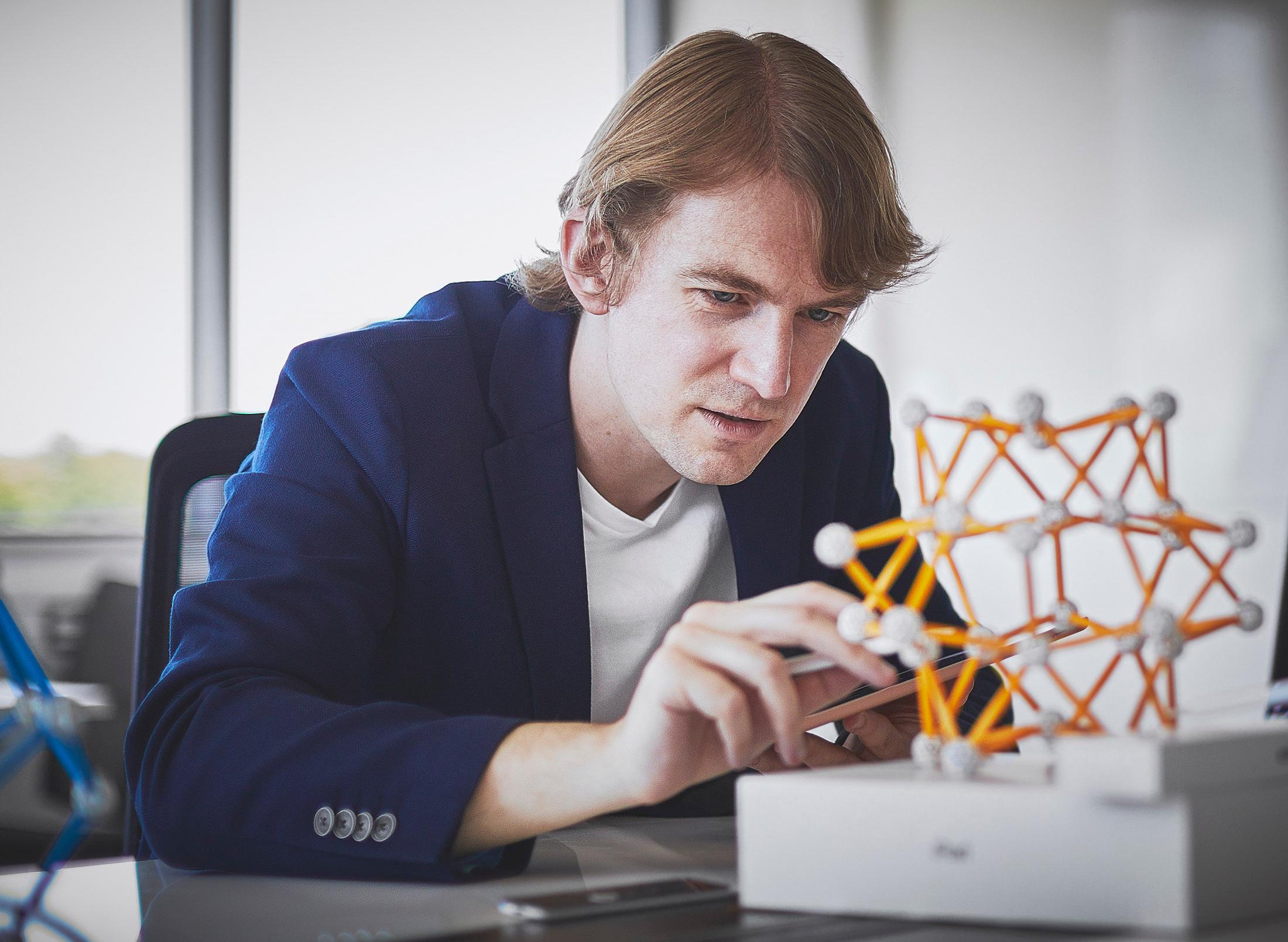 student works with 3D geometric structure made from straight pieces connected to joining pieces