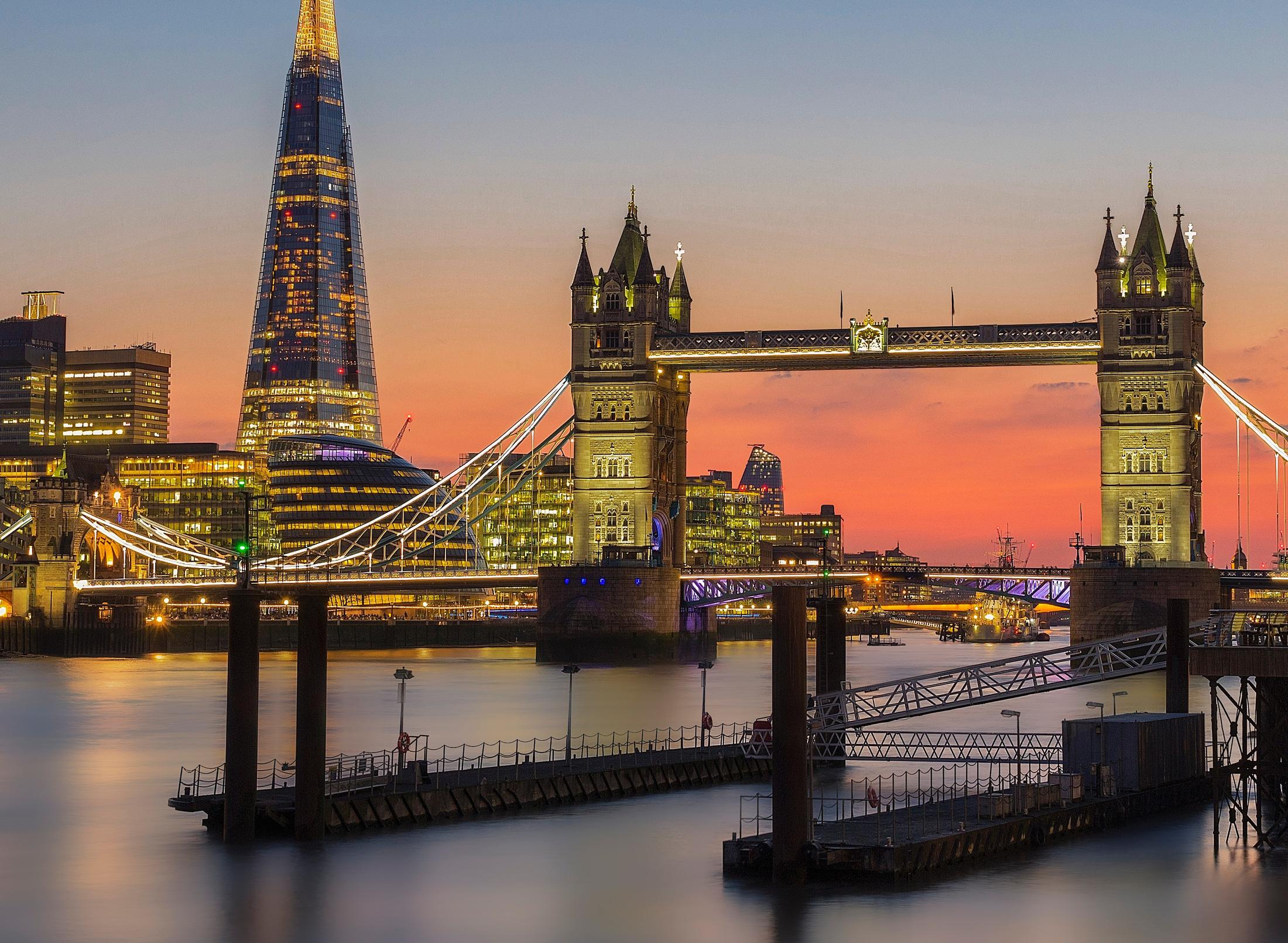 The Tower Bridge and The Shard building illuminated by the sunset, showcasing a beautiful skyline of London.