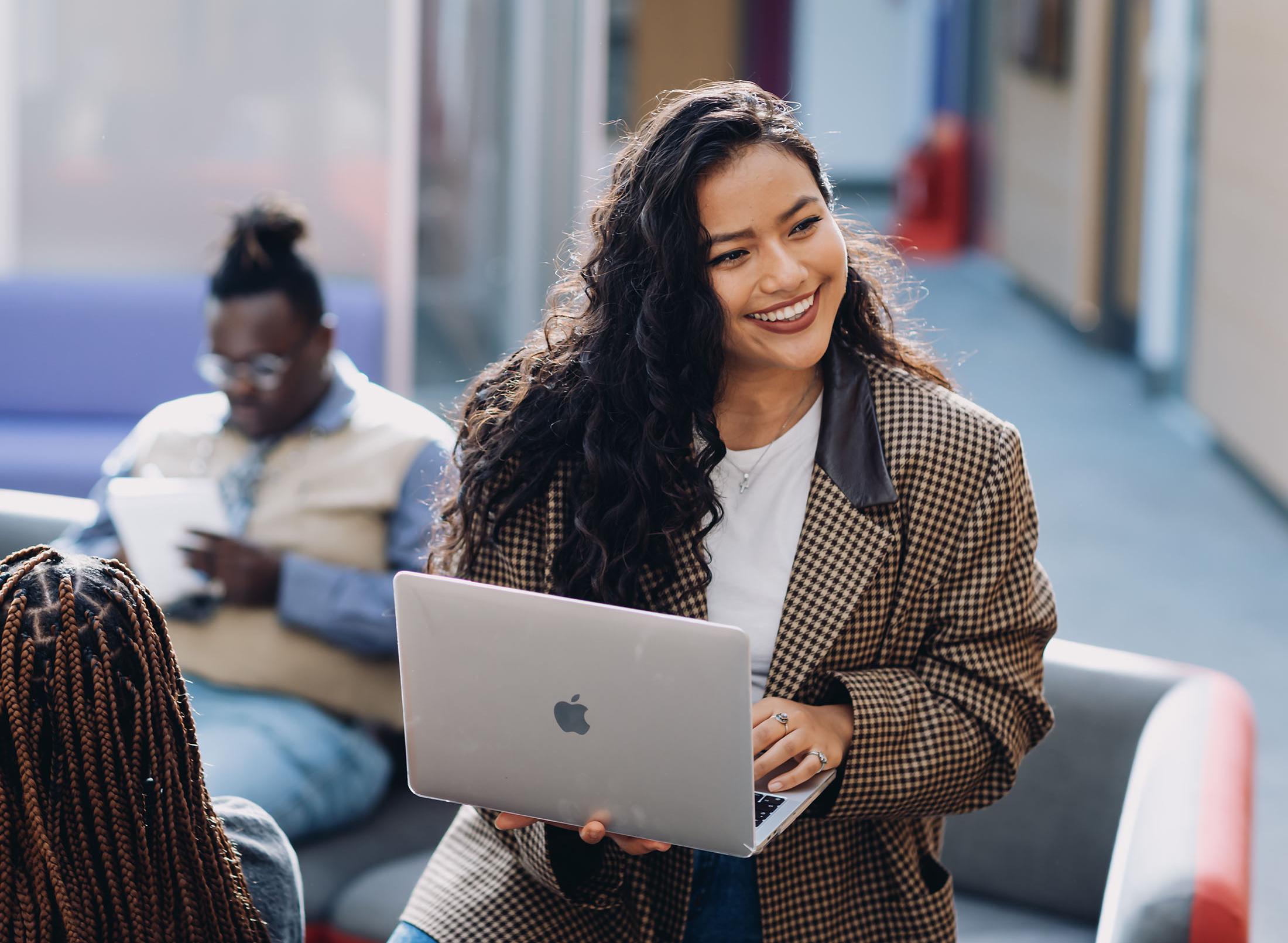 smiling student holding a laptop