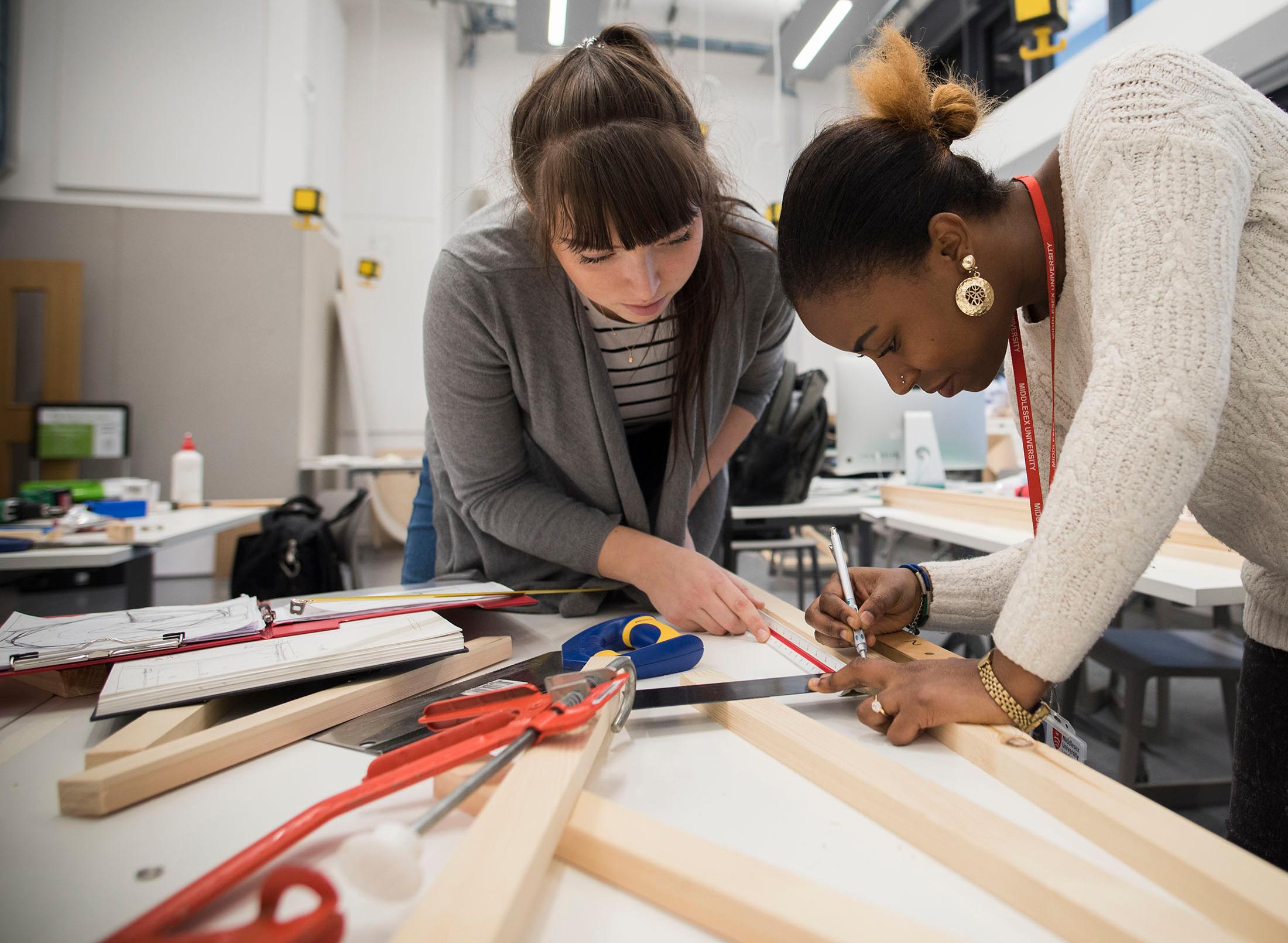 two students working together measuring and marking up wood