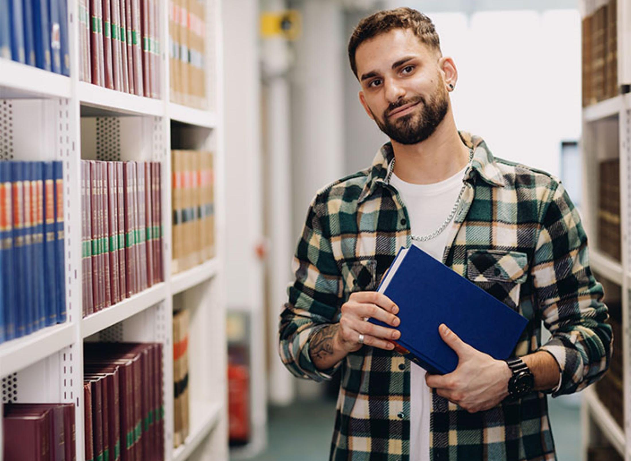 Male law student in the Sheppard Library standing between book shelves