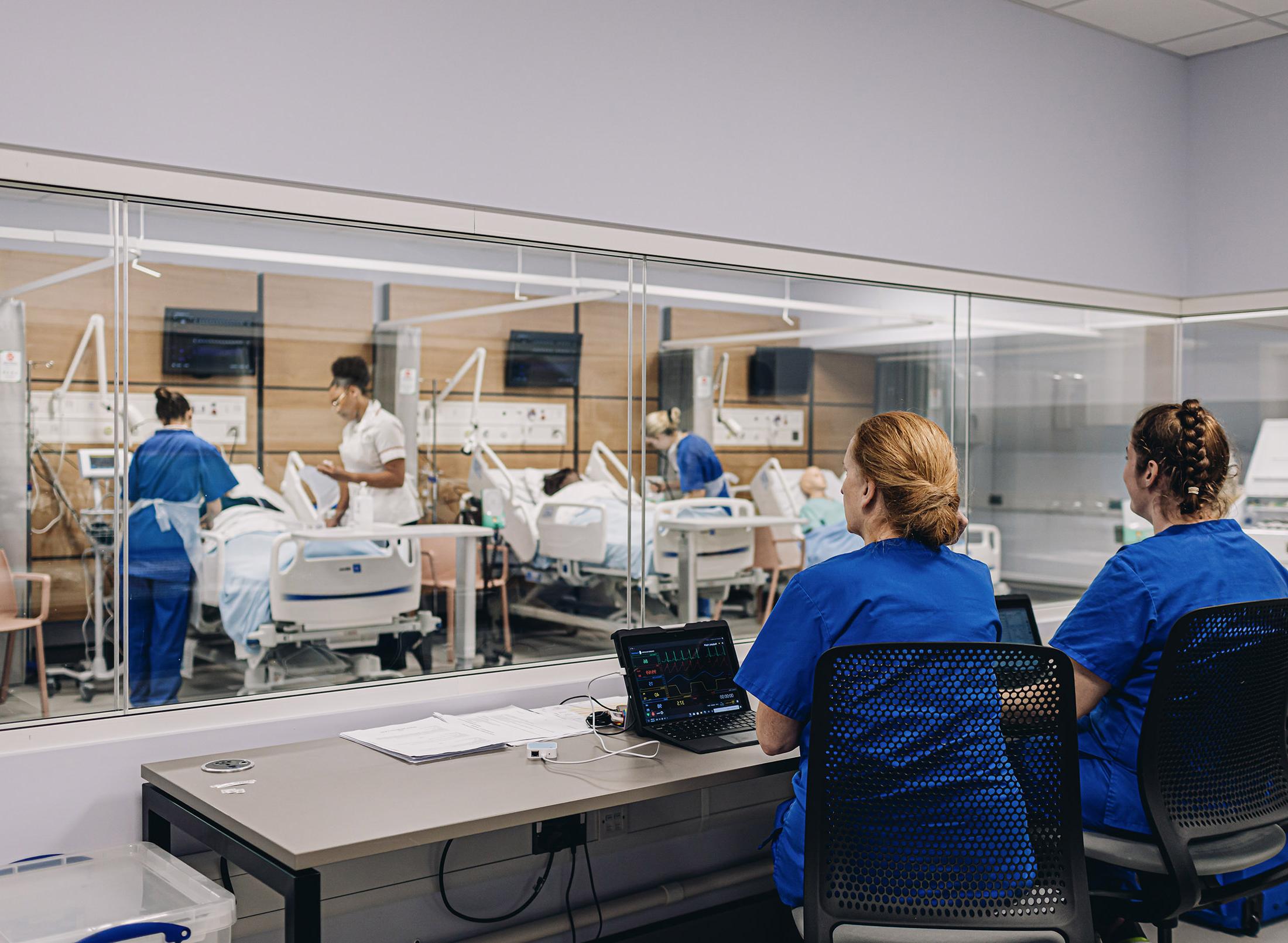 Nurses watch on from control panel as colleagues work with patients in bed