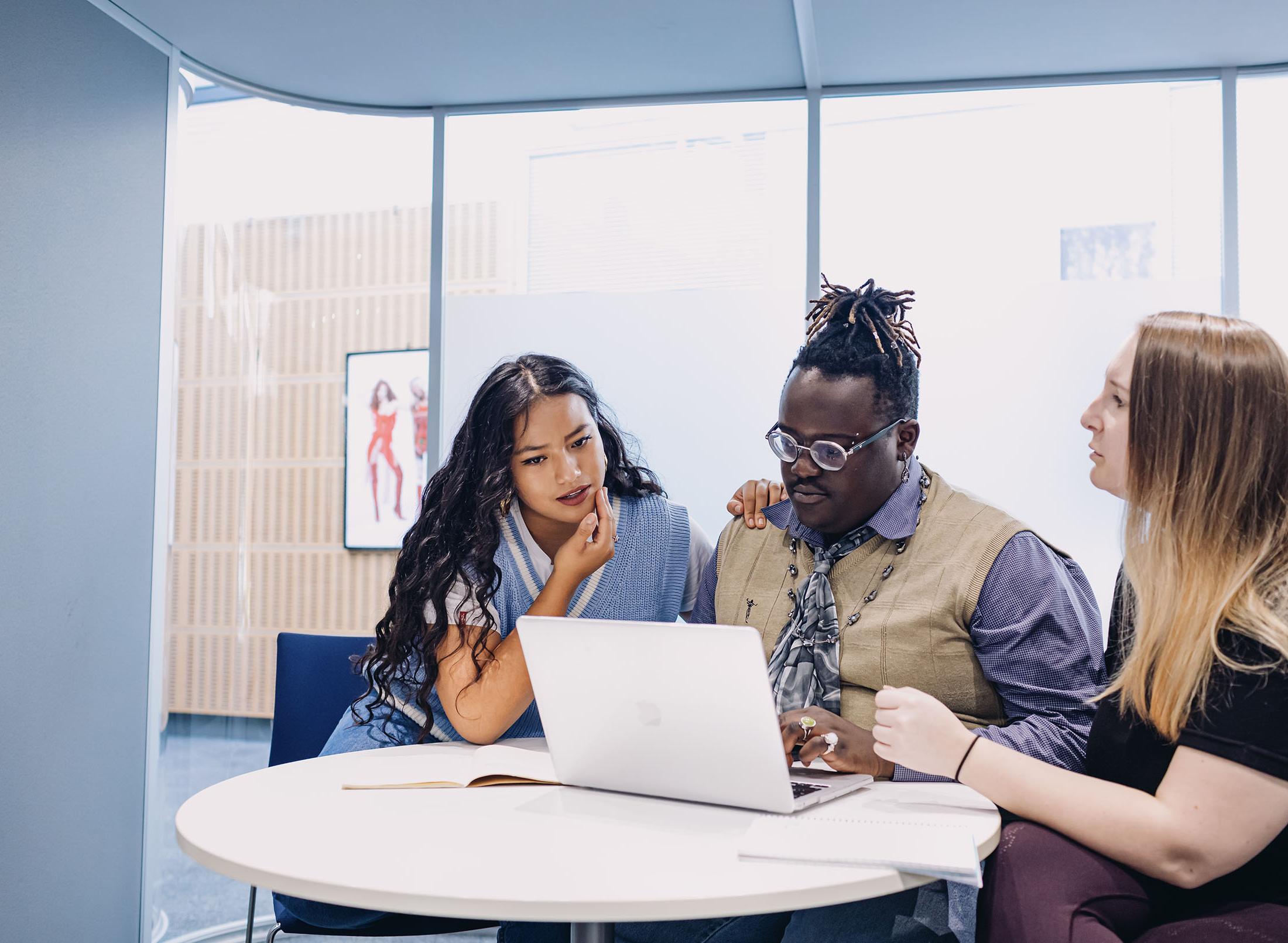 three students work together on laptop