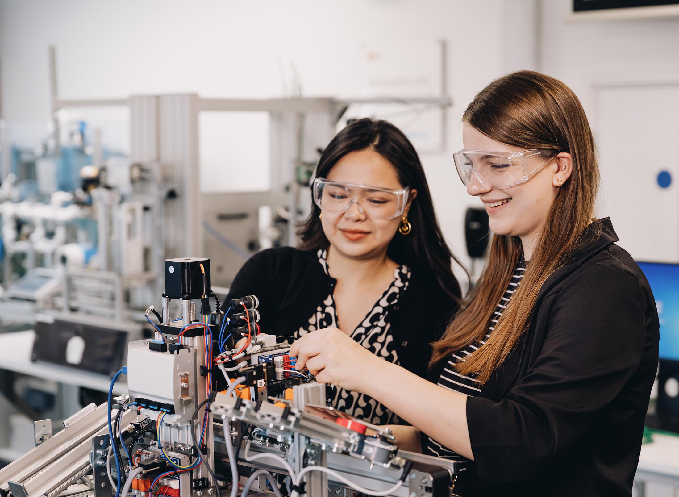 Two students wearing goggles work on mechatronics project together