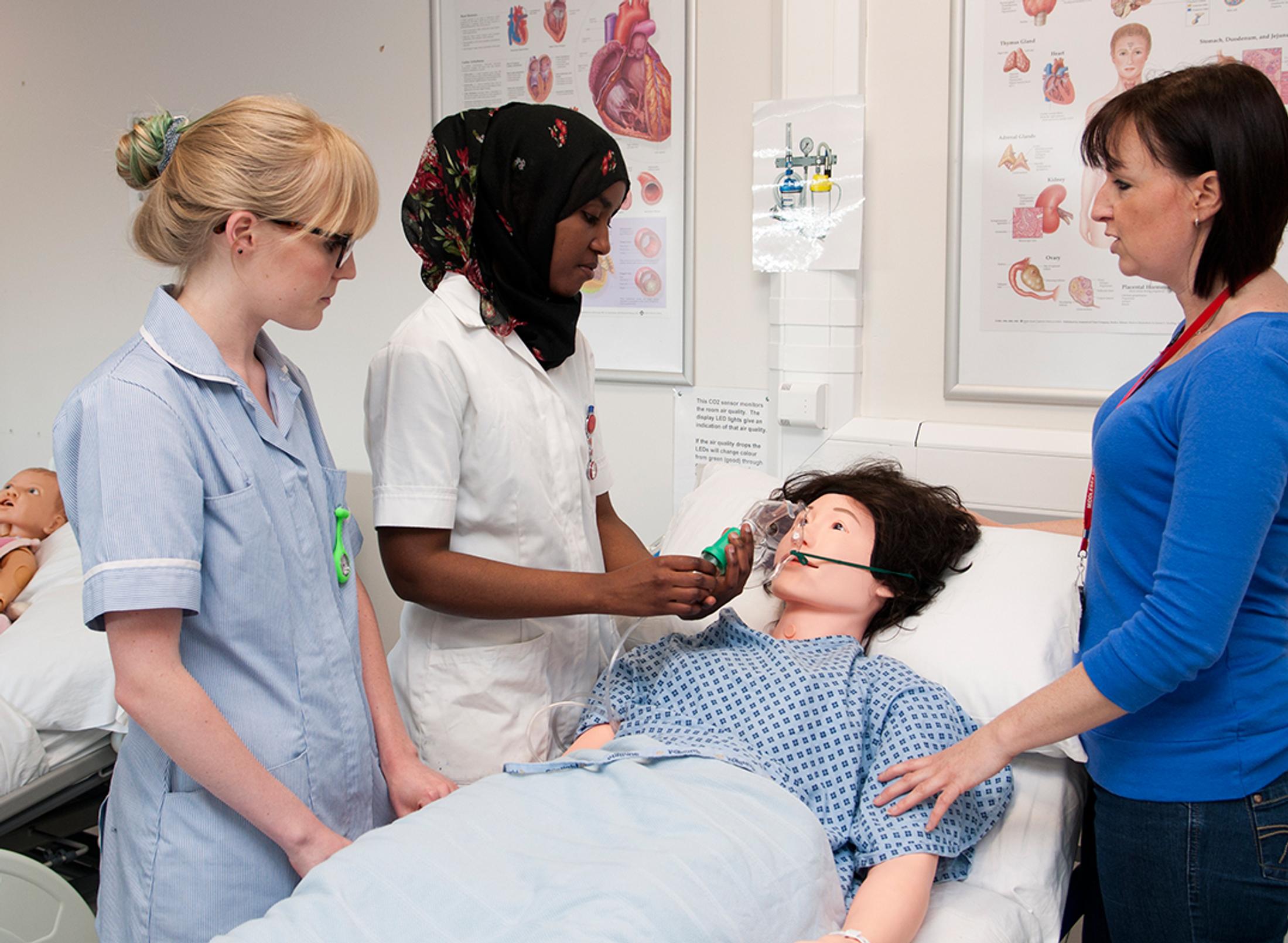 student nurses examining a dummy in class