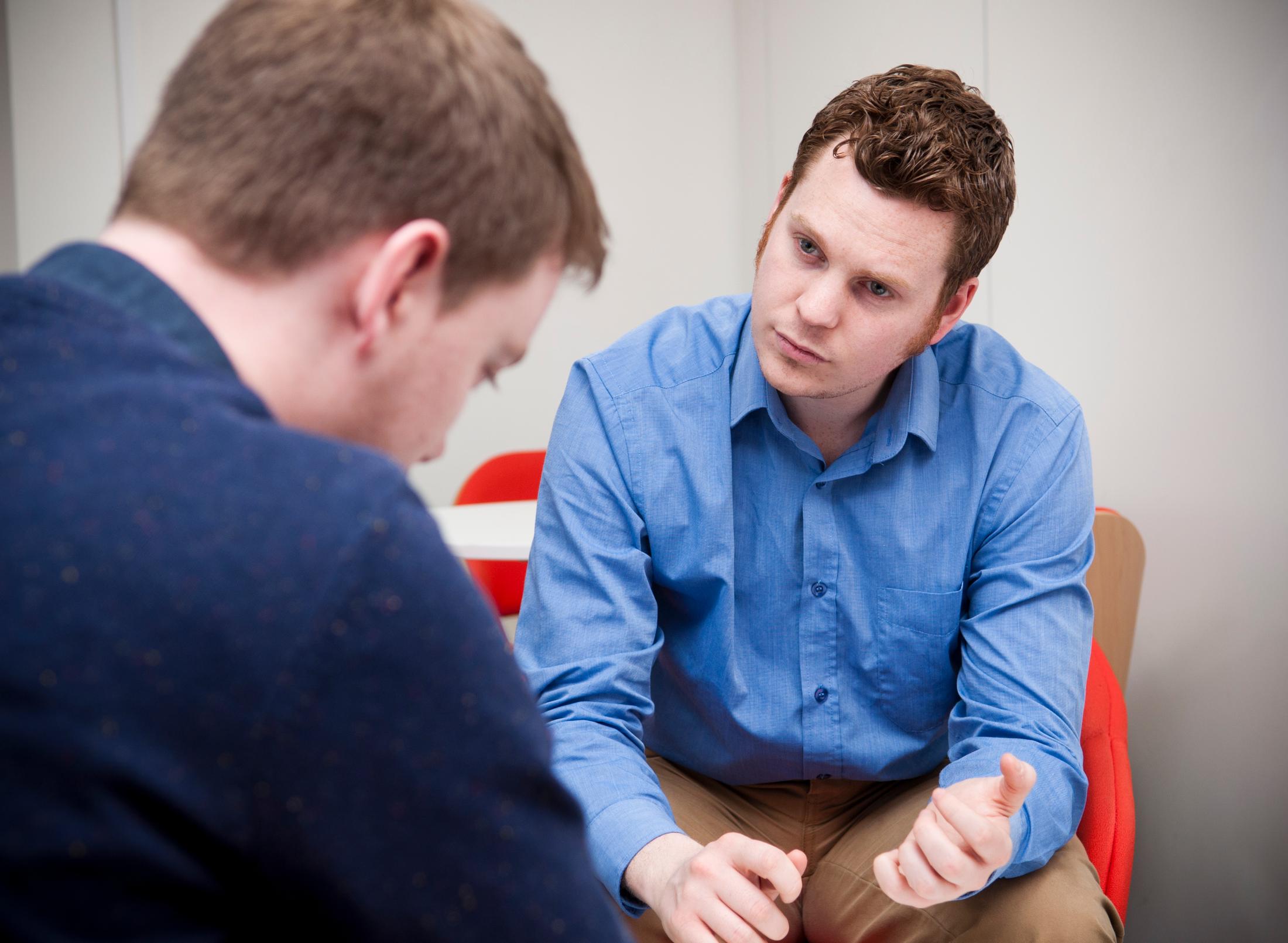 A person sitting on a couch talking to a therapist. They are engaged in a conversation about mental health and social work.