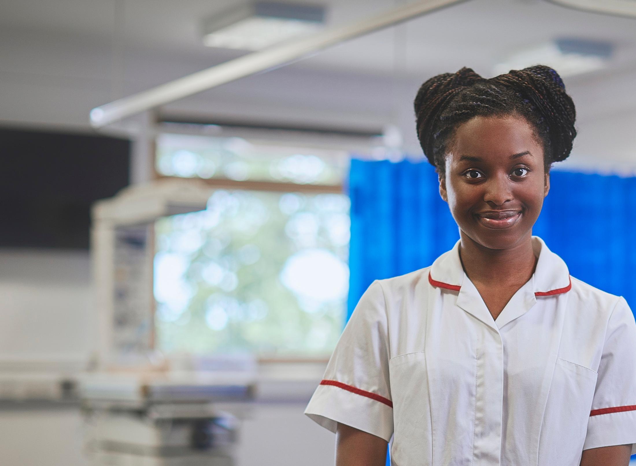 Two nurses assisting a baby in a hospital room.