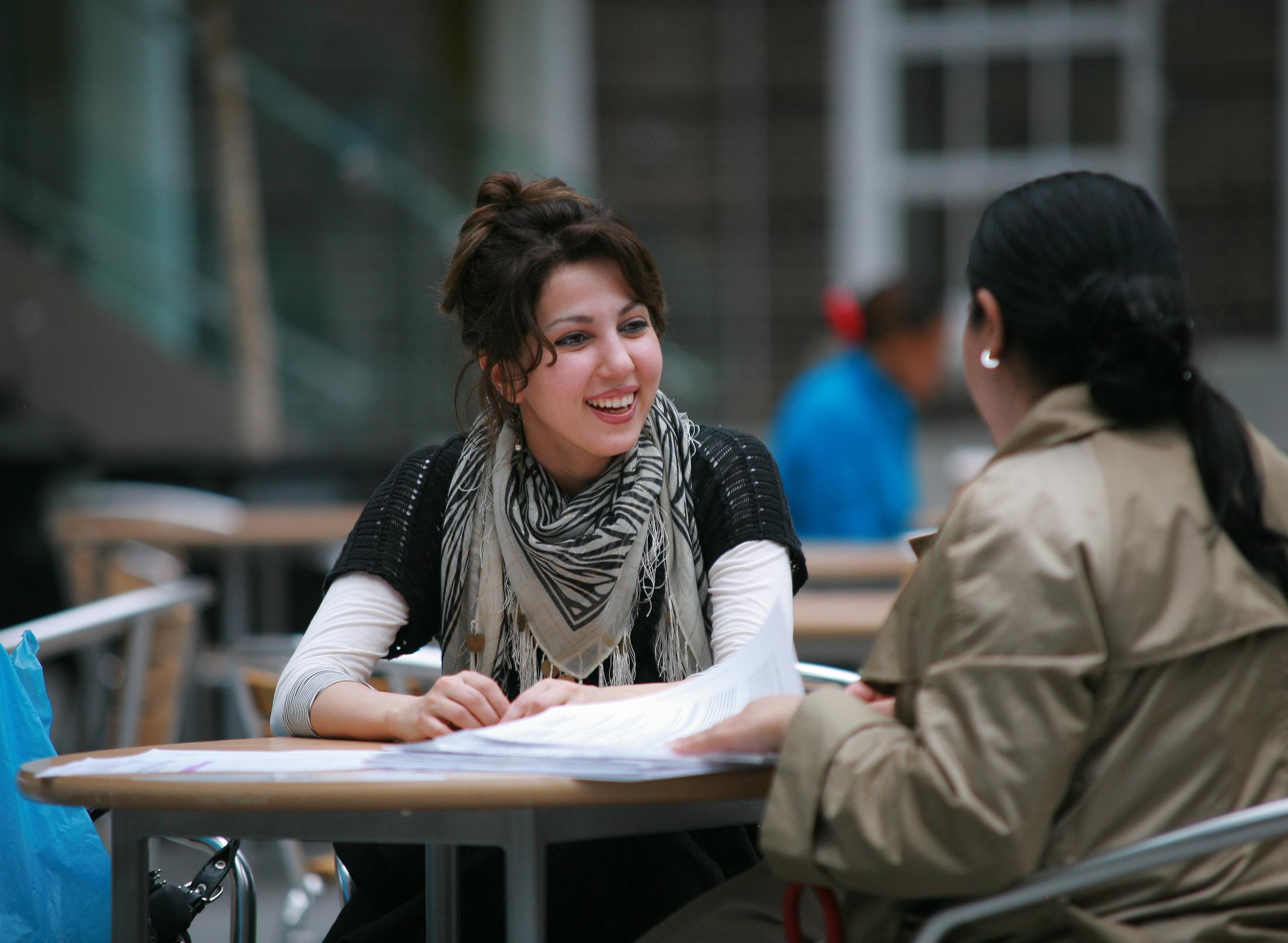 Two women sitting at a table, engaged in conversation and enjoying each other's company.