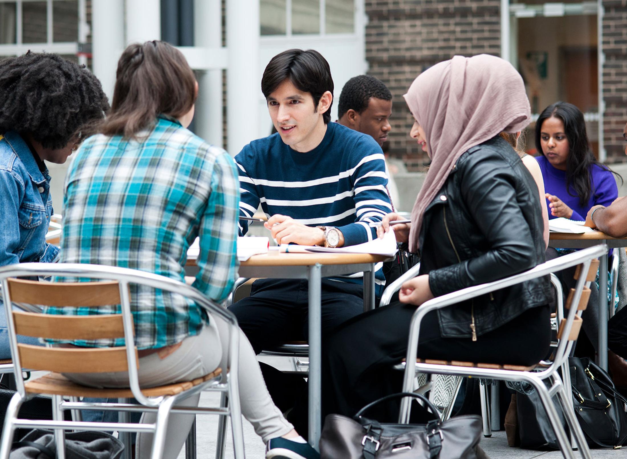 A group of middlesex students sit at tables in the quad