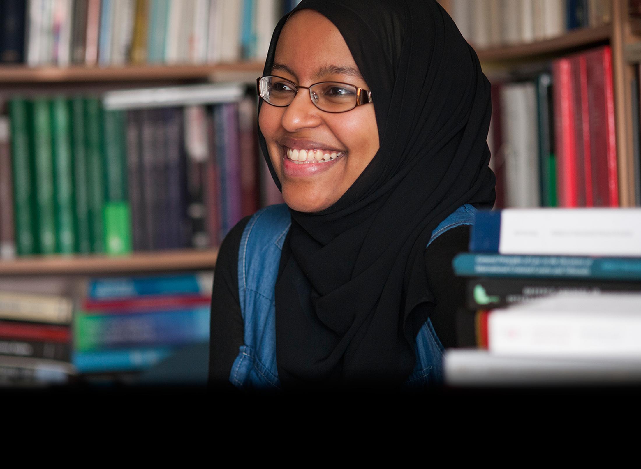 A Muslim female student smiling in a library