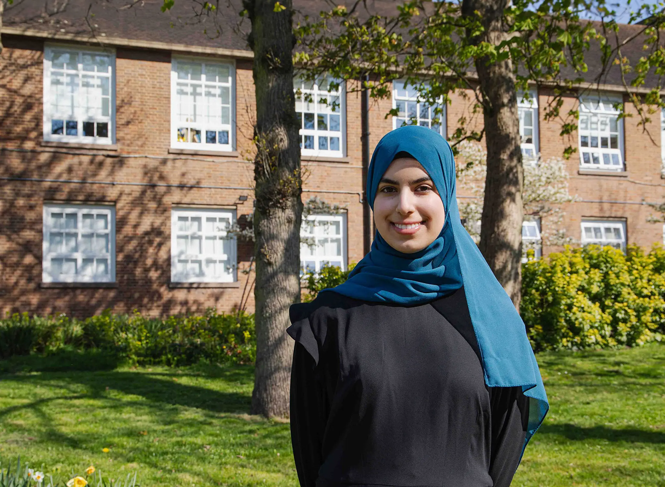 Student Duha posing in front of red bricked building