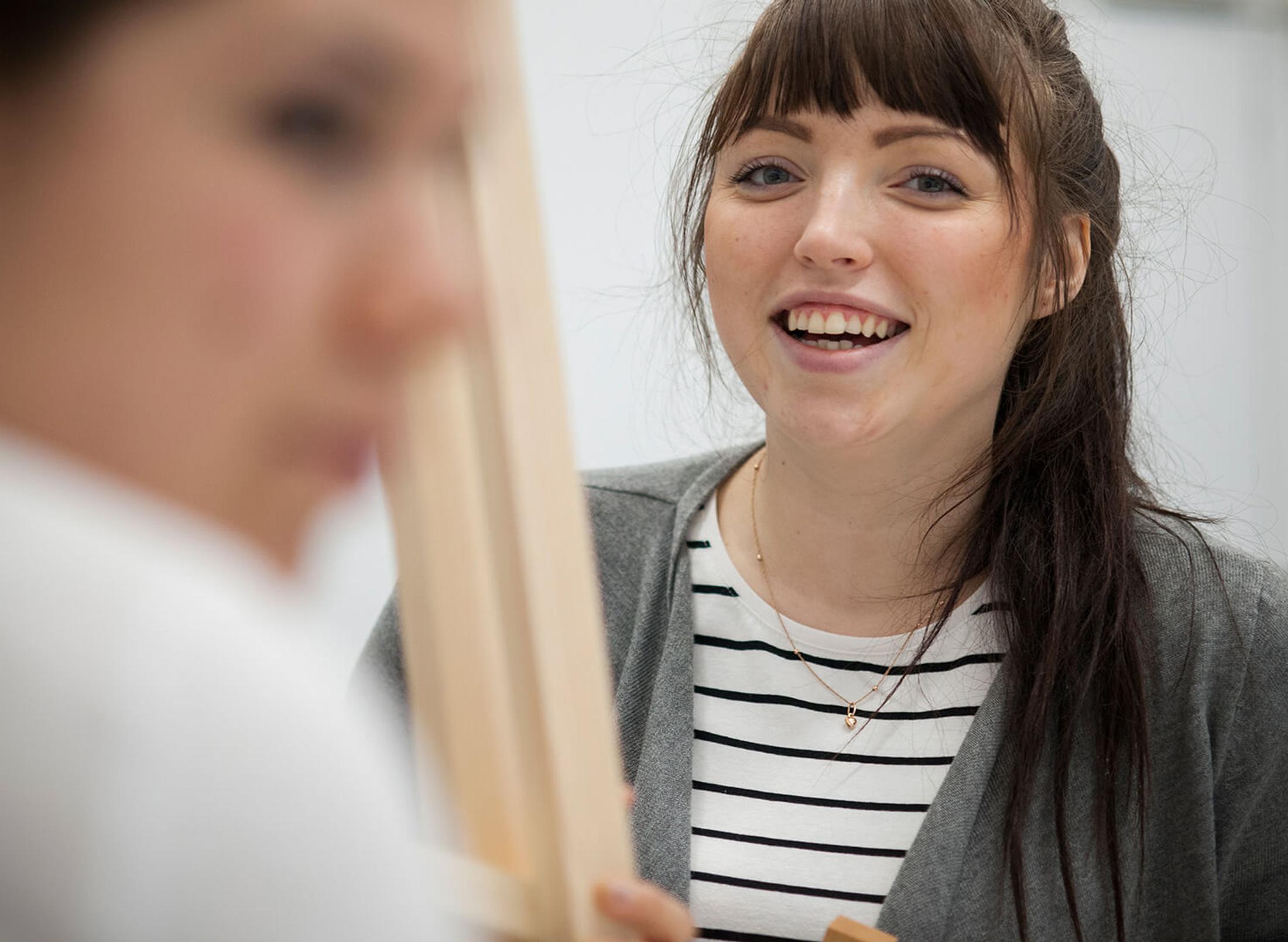 Smiling middlesex uni student holding a skirting board