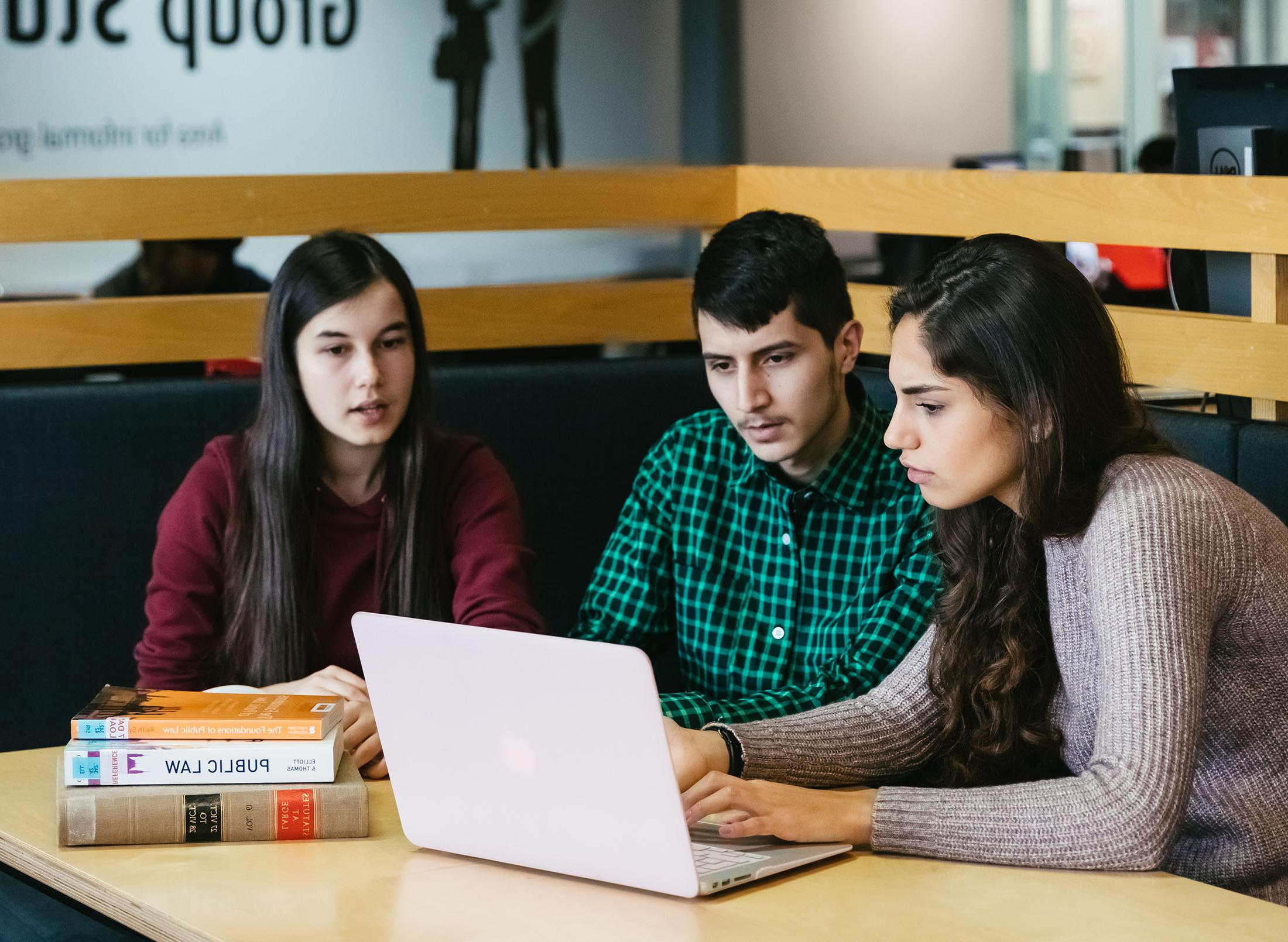 three students studying together in a library
