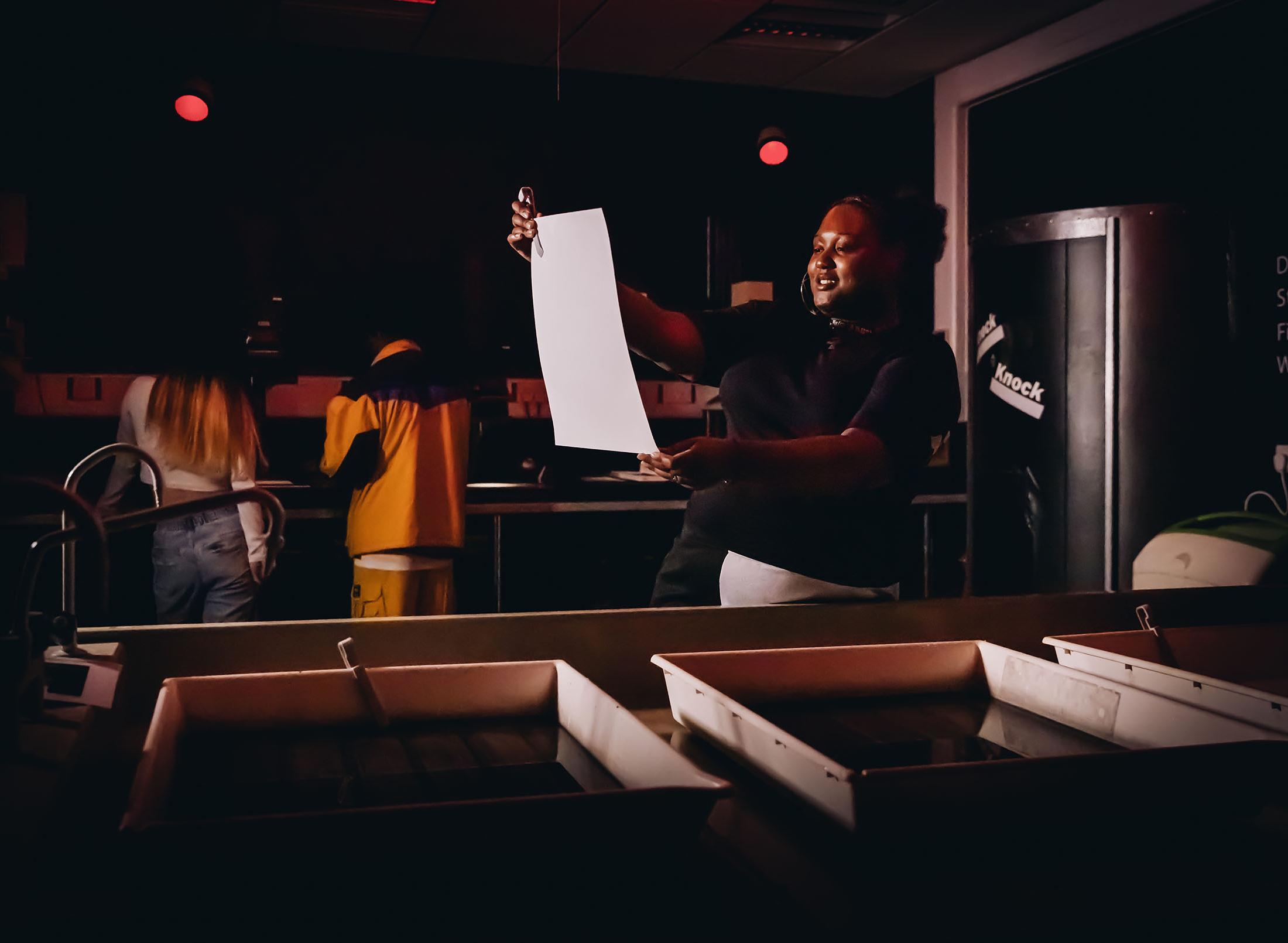 student working in darkroom looking at work