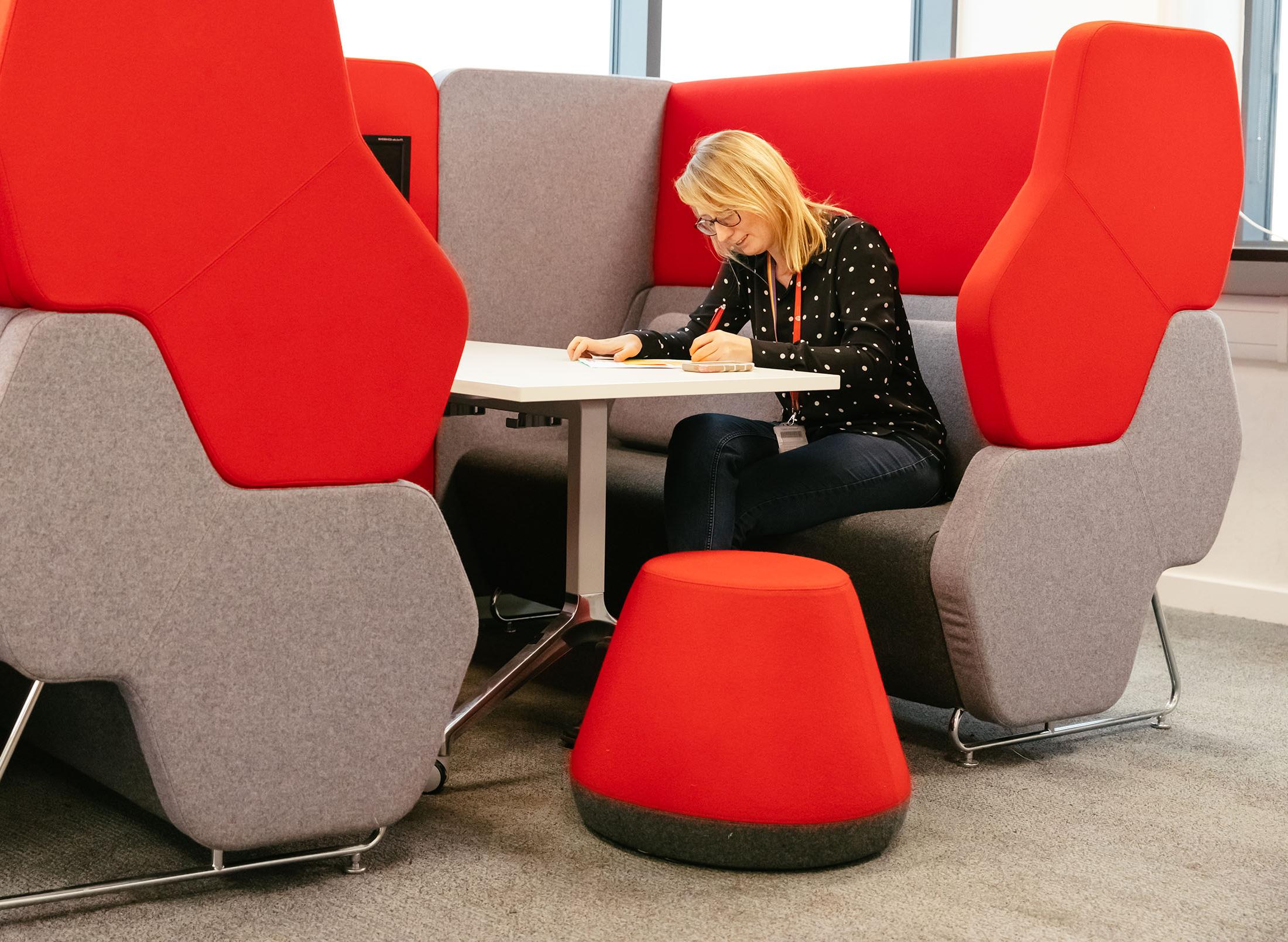 Woman sitting in red seating booth making notes on paper