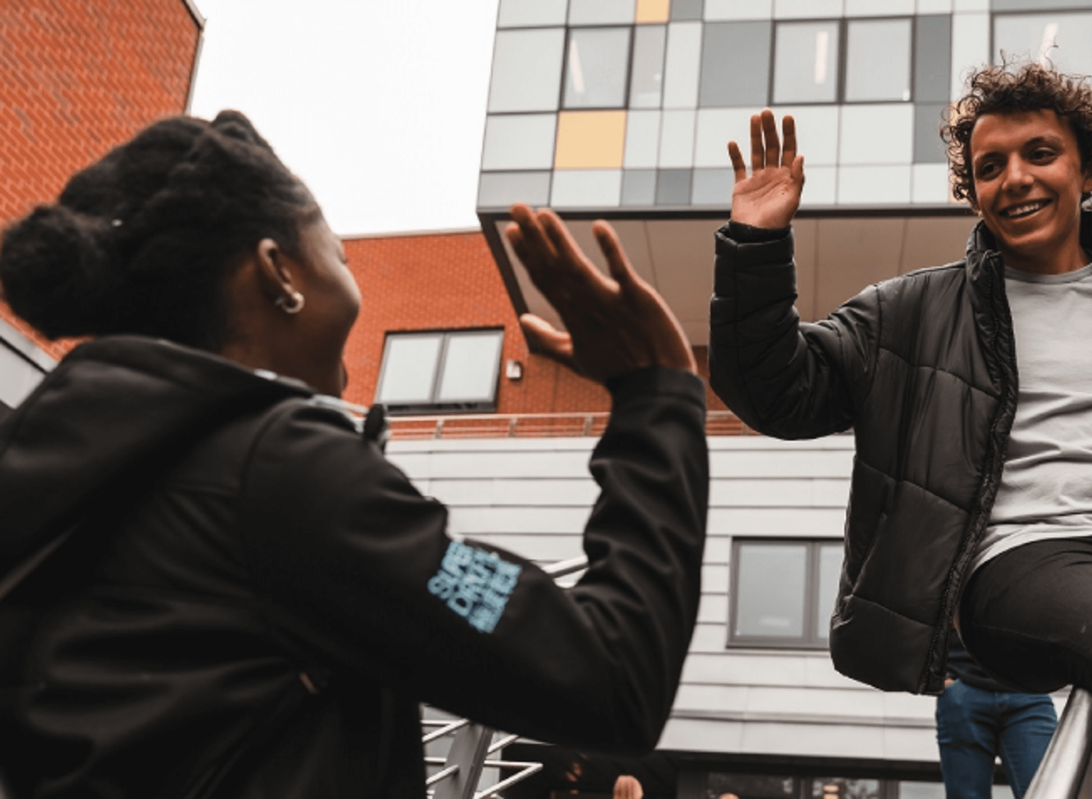 Two students celebrating their success by giving each other a high five.