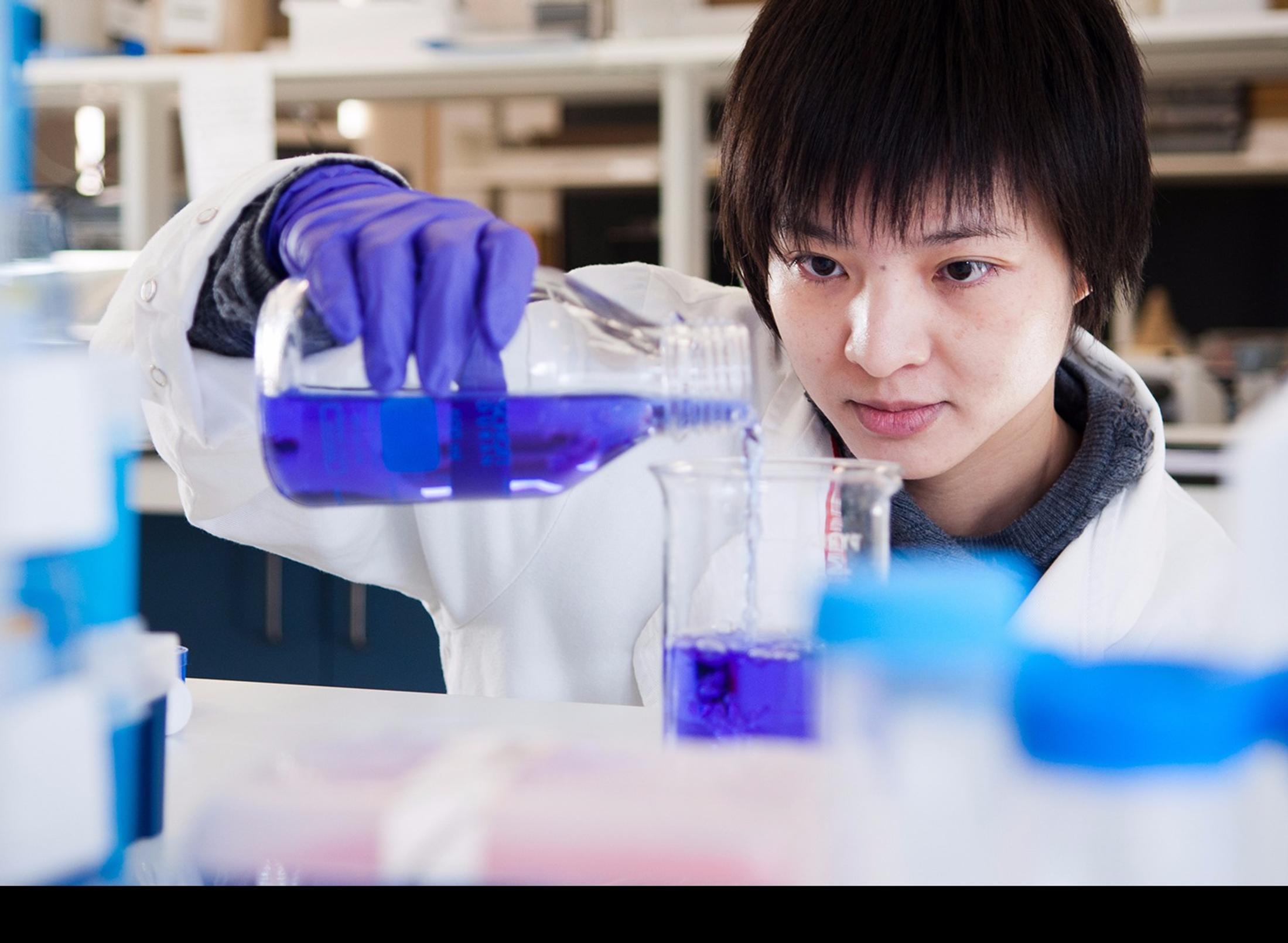 Female student in white lab coat prepares a liquid experiment in the lab at middlesex university