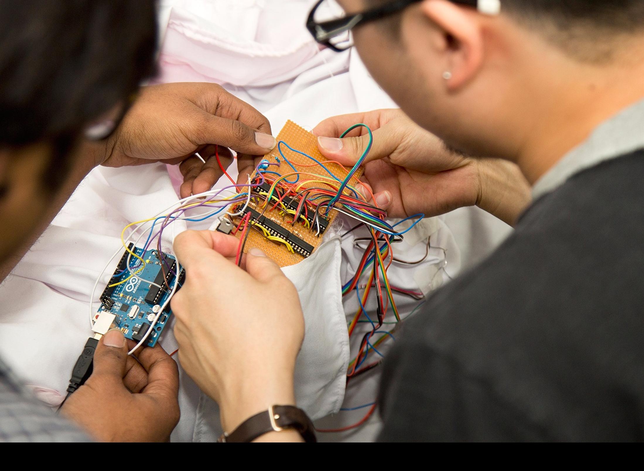 Two male students sitting at a desk, working on a piece of electronic equipment