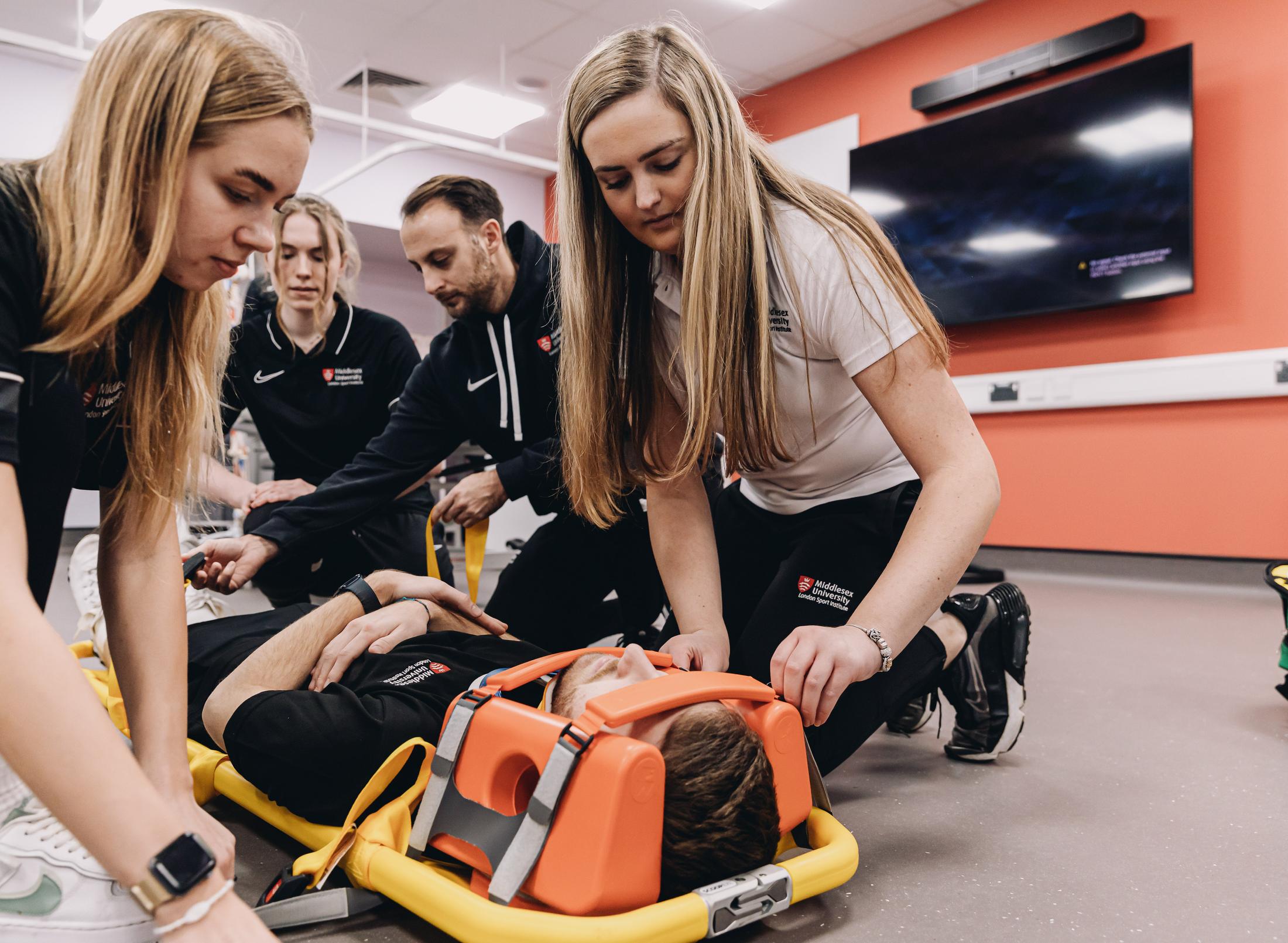 A group of people at WestStand working together on an emergency stretcher to provide immediate medical assistance.