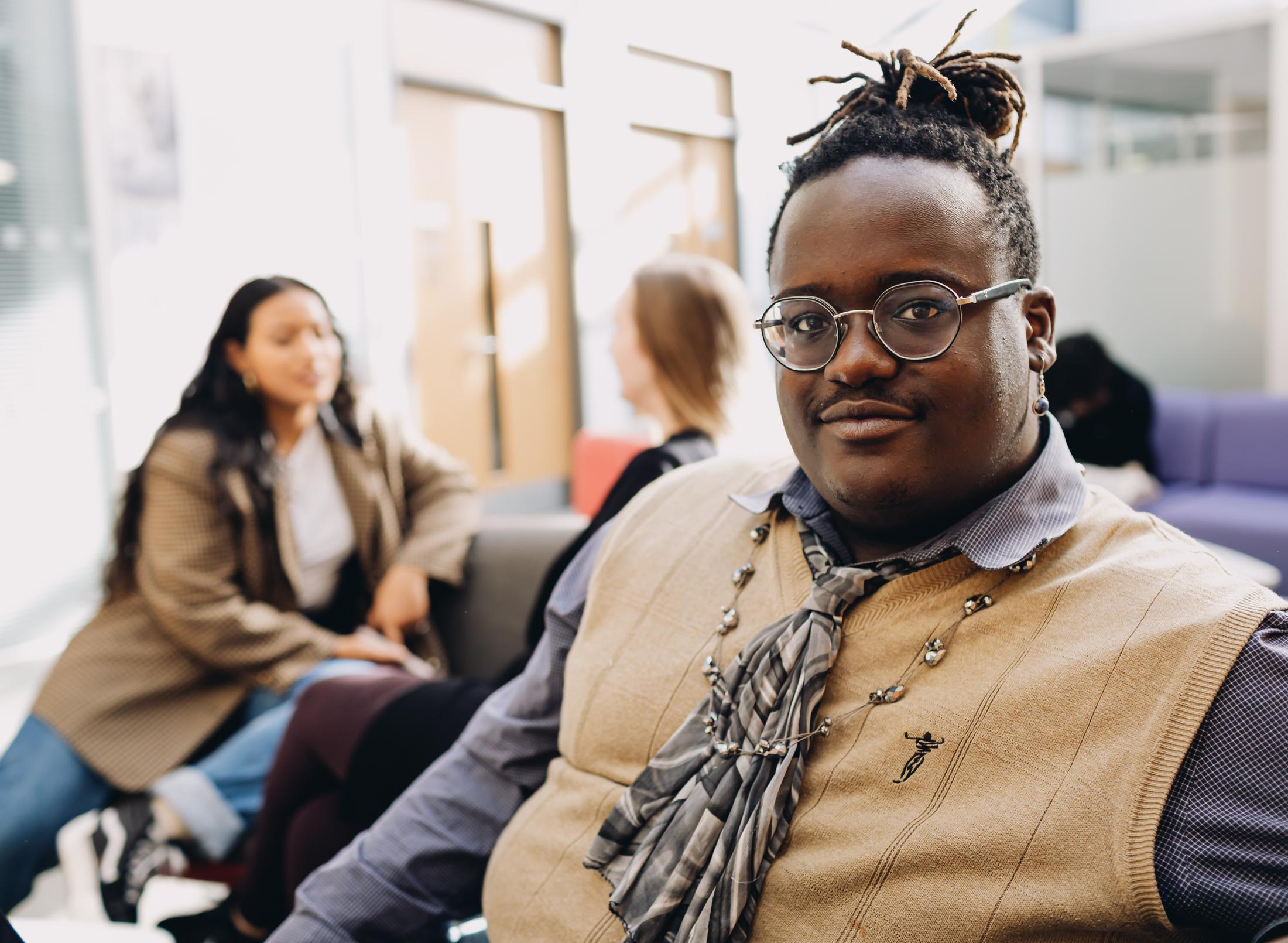 A man with dreadlocks sitting in a chair with a group of people.