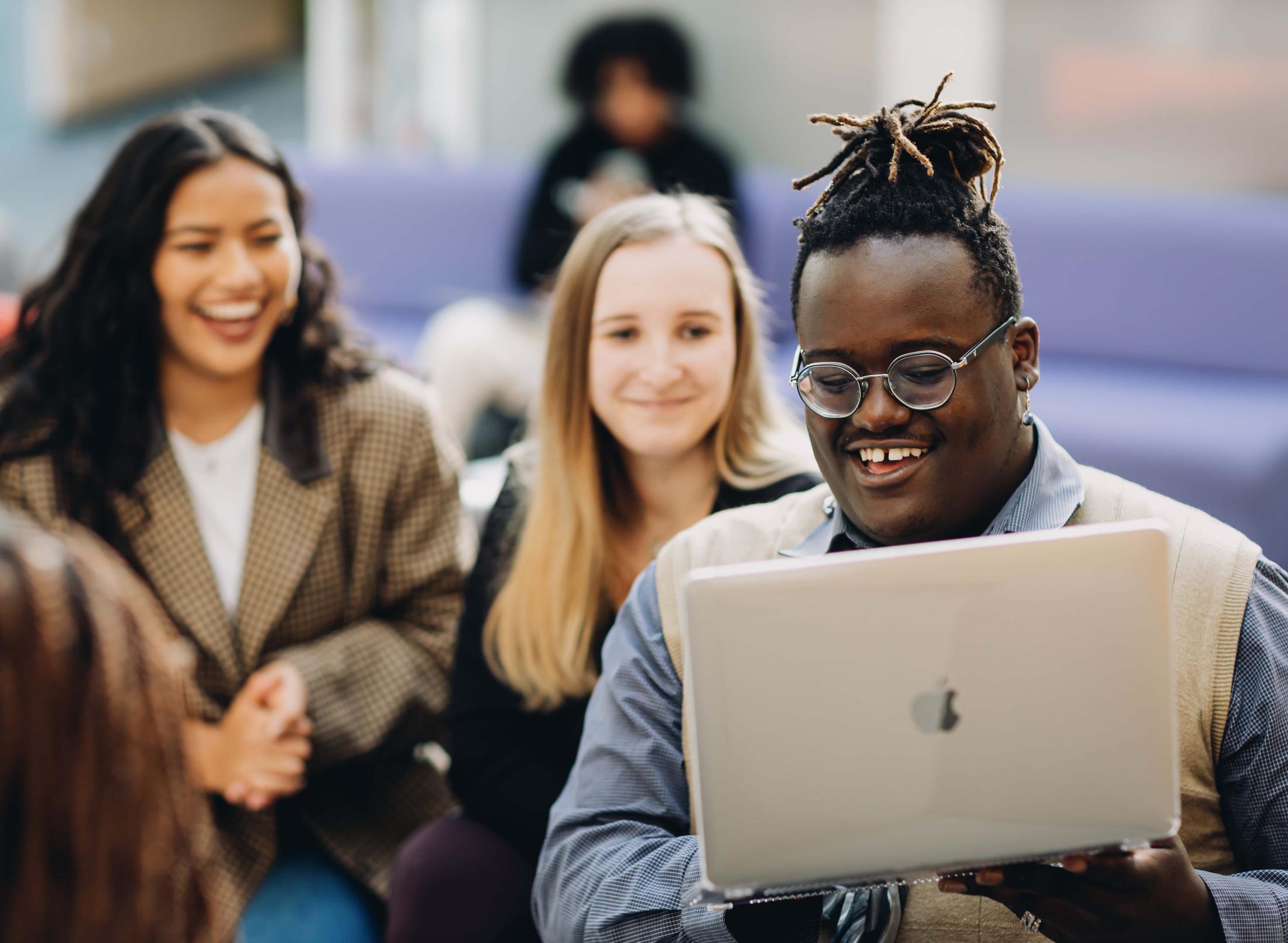 Three students looking at a laptop