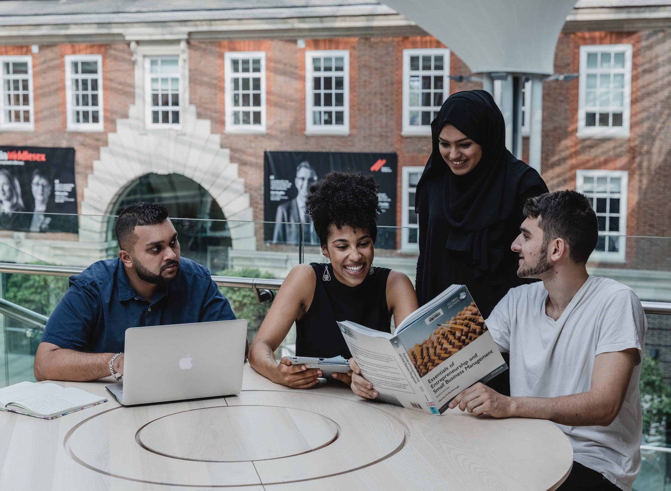 four business management students working together in the quad