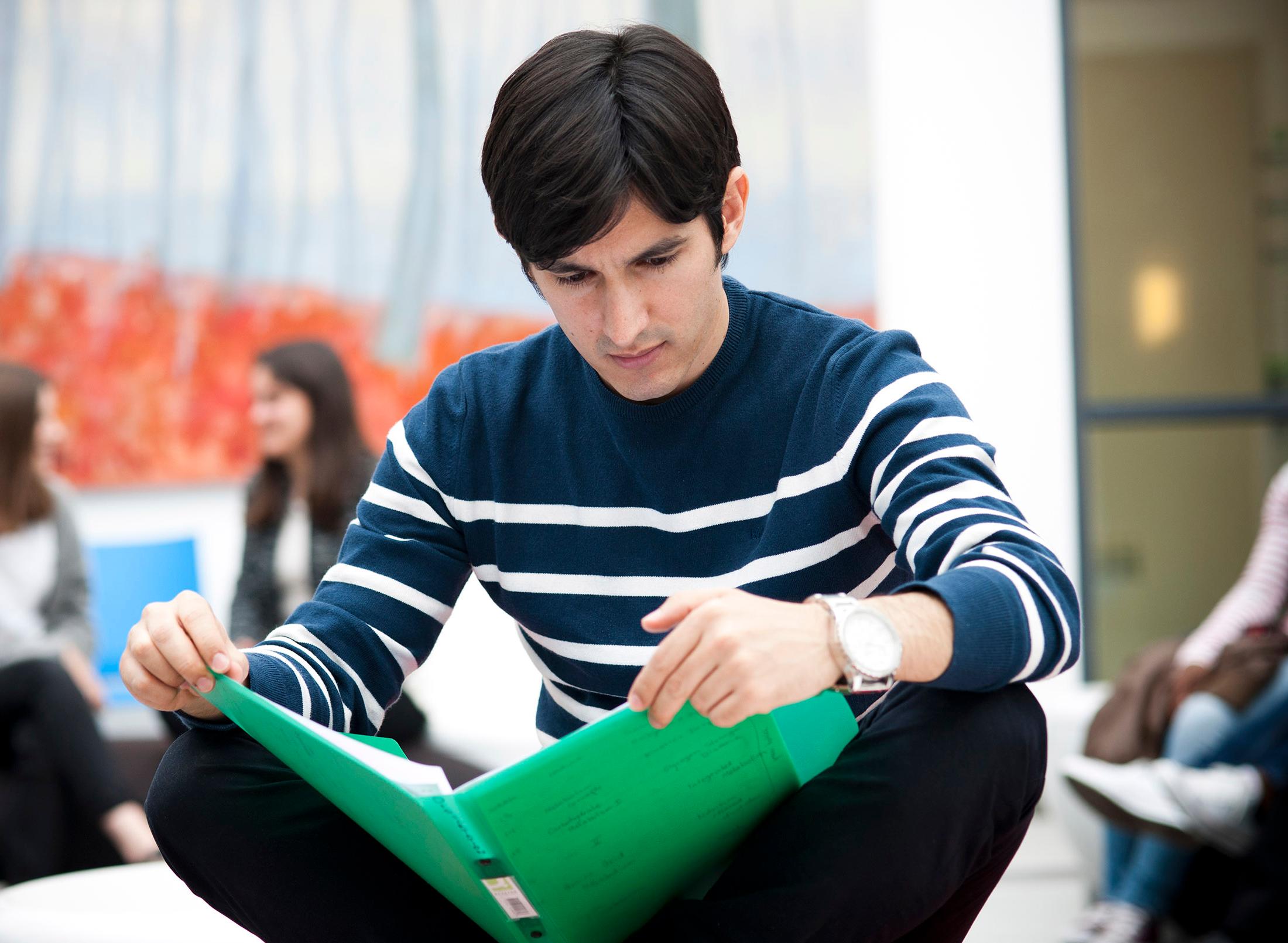 sitting student reading folder