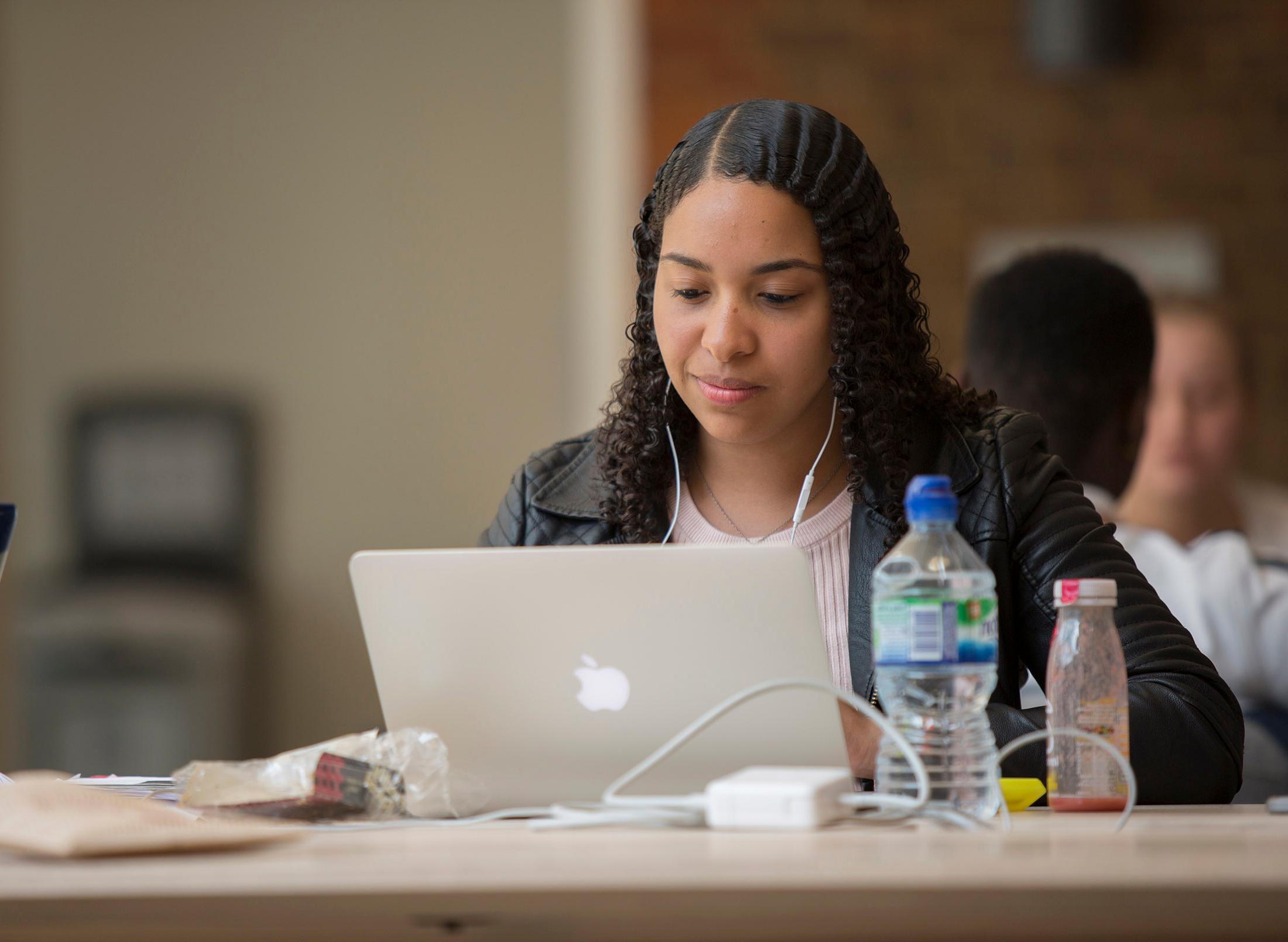 Student studies at computer, with bottles of drinks next to her