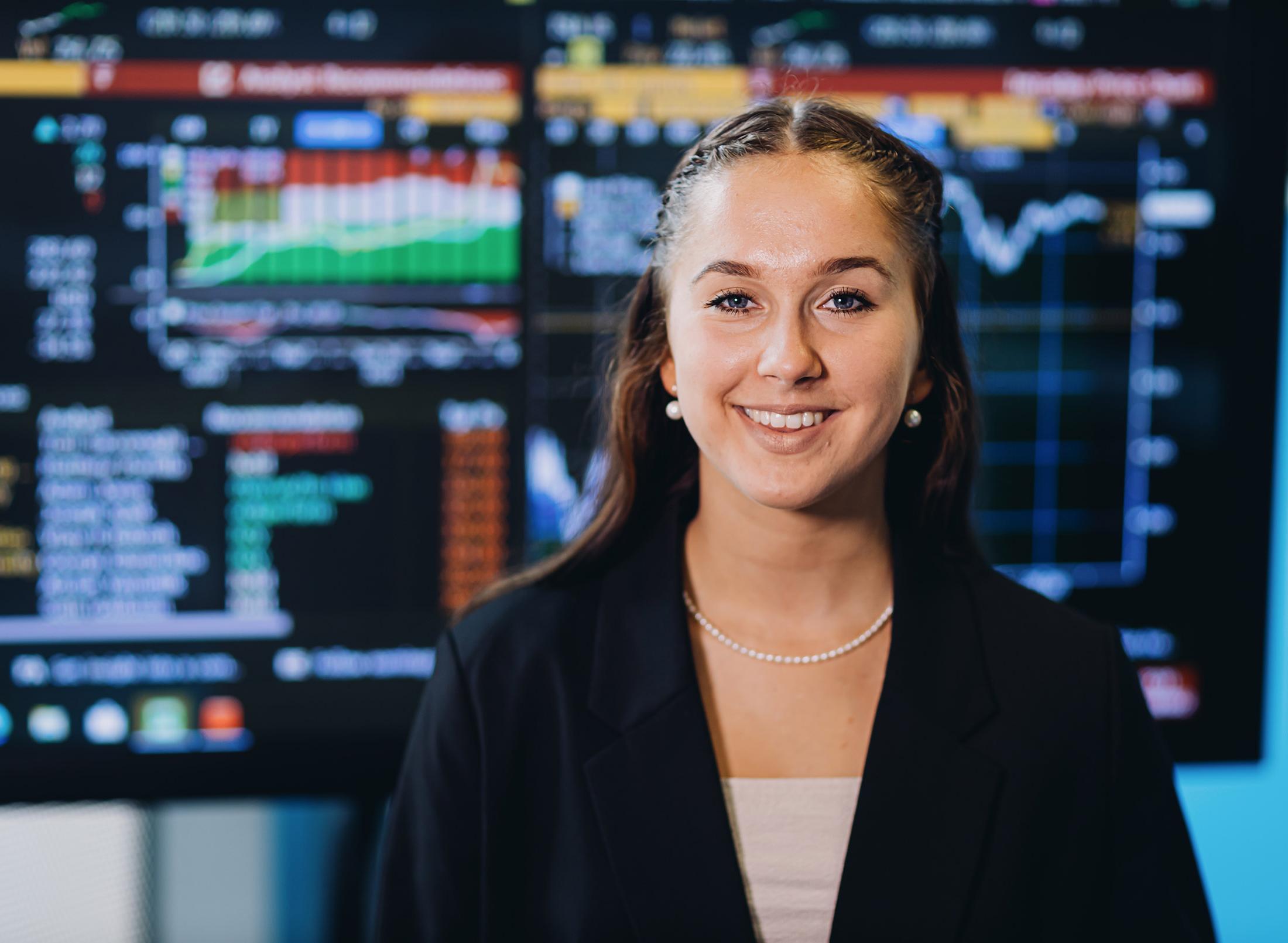 student stands in front of finance display