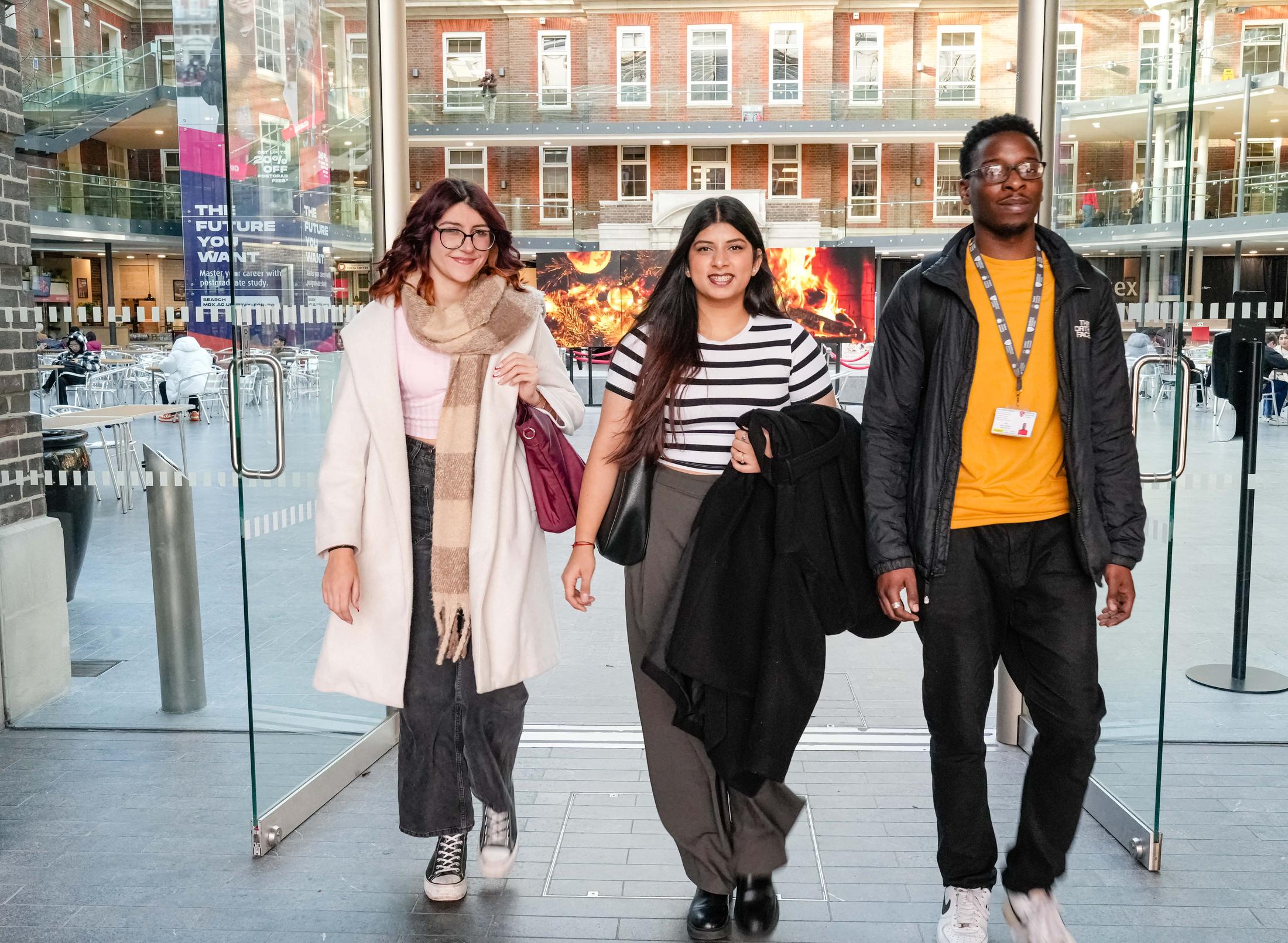 3 students walking in the atrium