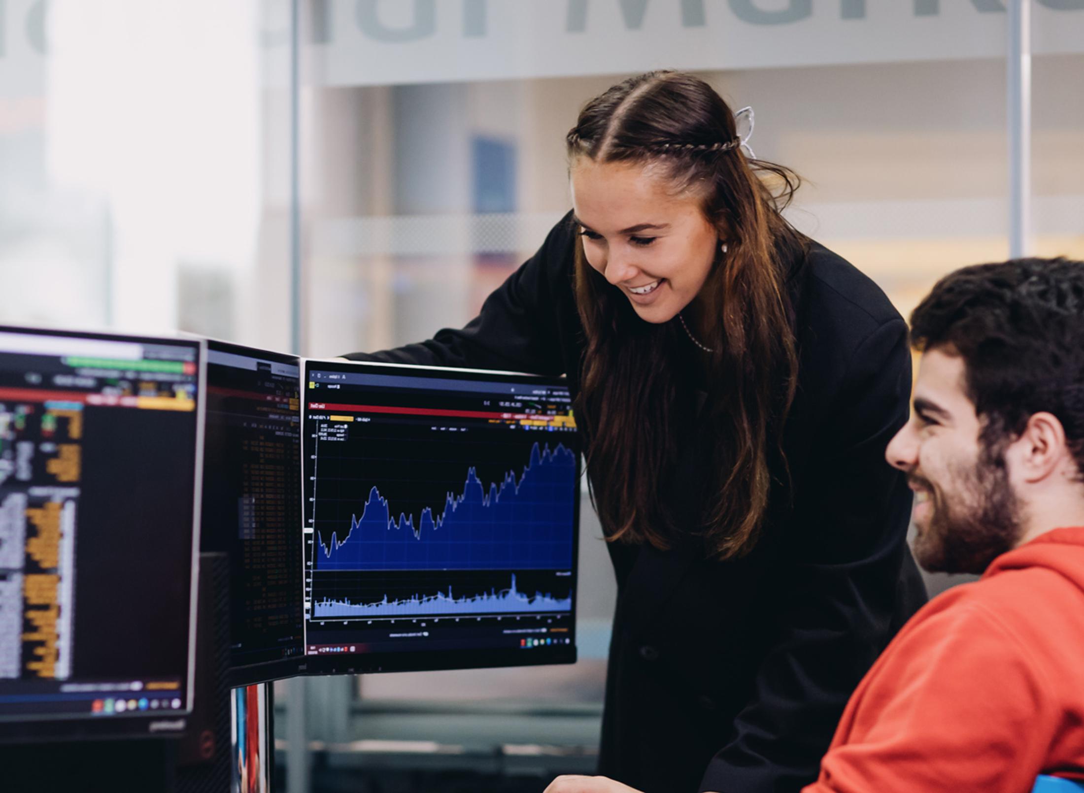 Students in a financial lab environment in a university setting looking at graphs on two screens