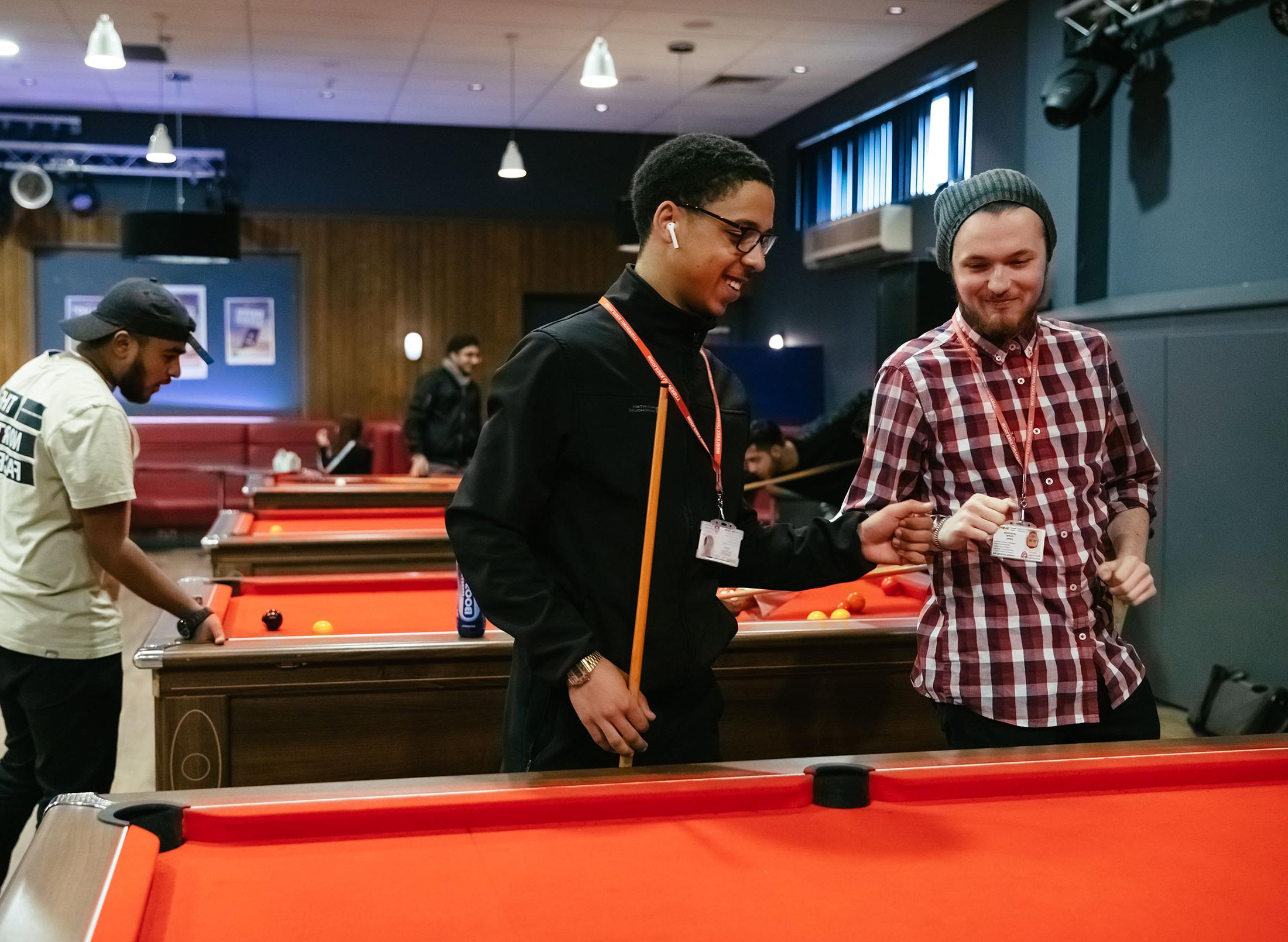 two students stand at pool table ready to play game