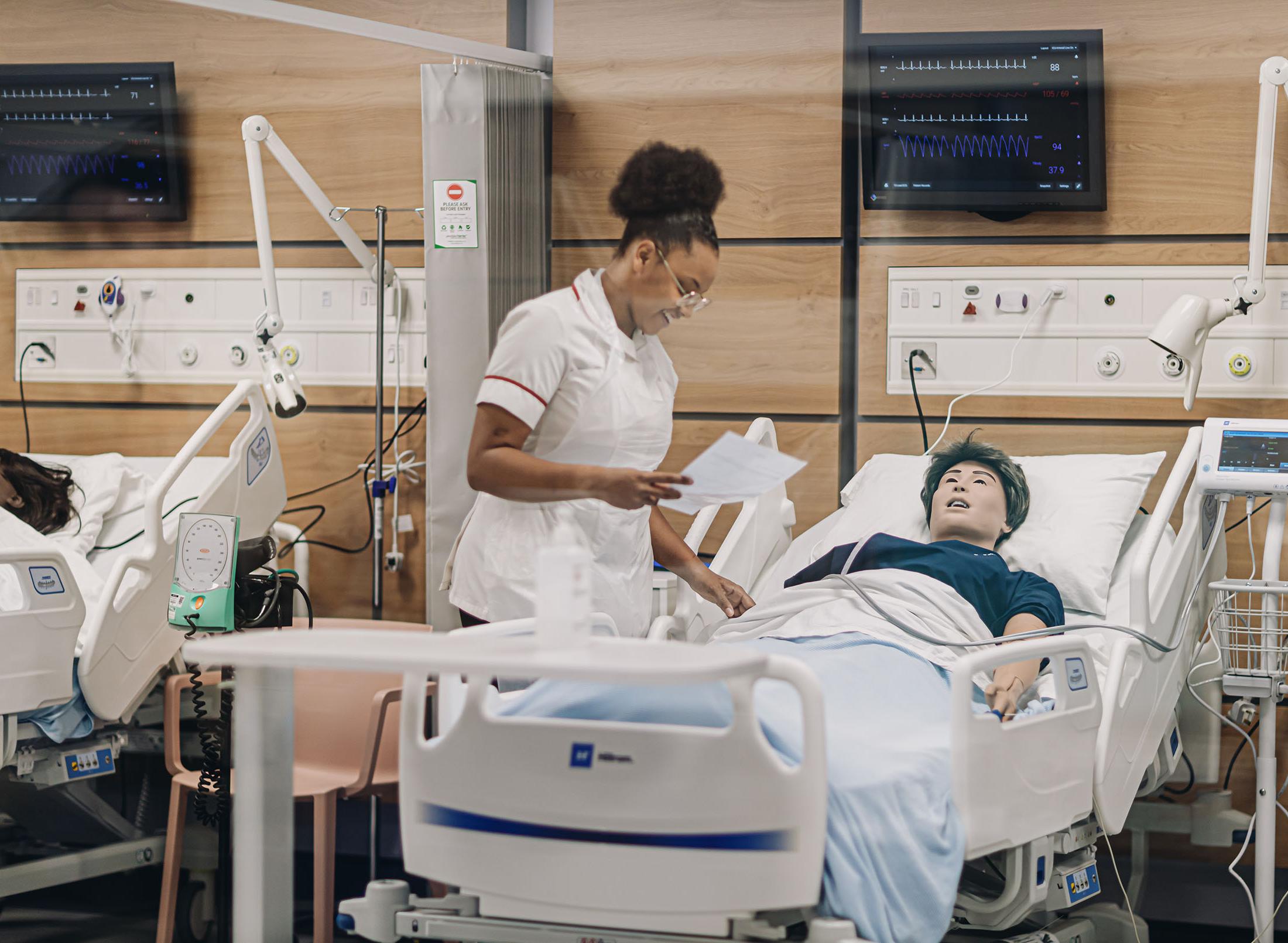 A nurse stands next to a dummy in a hospital bed