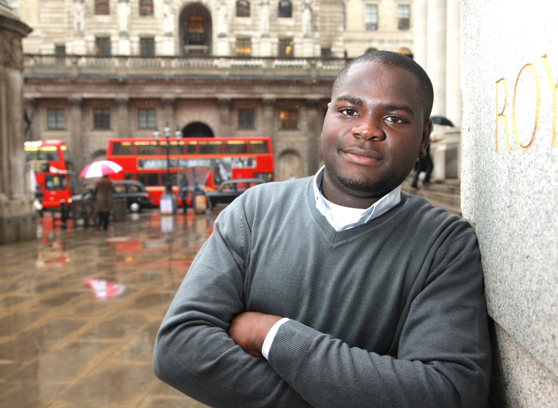 Student in a grey sweater and shirt standing outside in the City of London.
