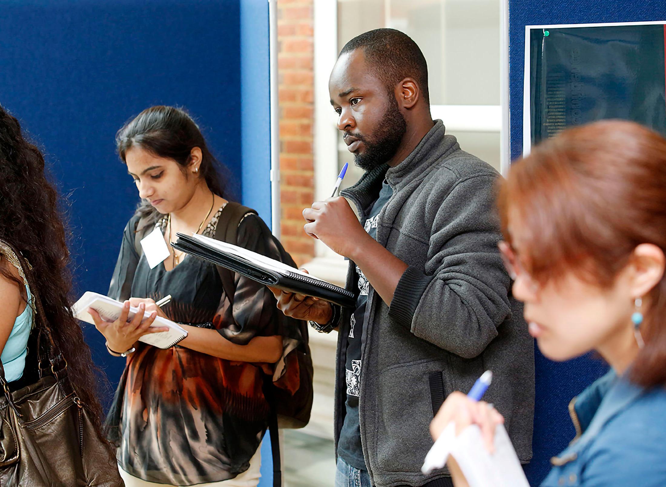 research students at conference taking notes on clipboards