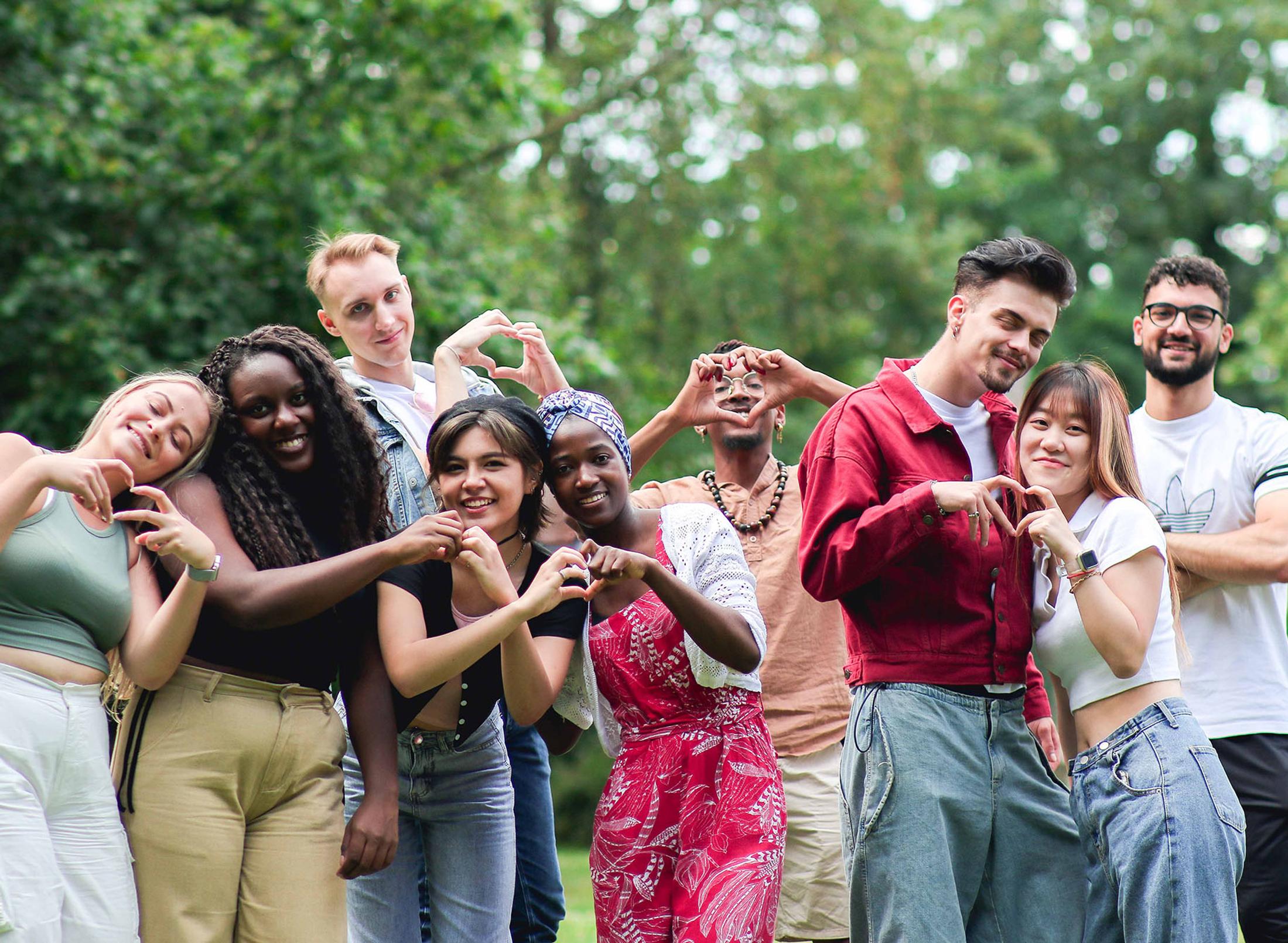large group of happy students make heart shapes with their hands