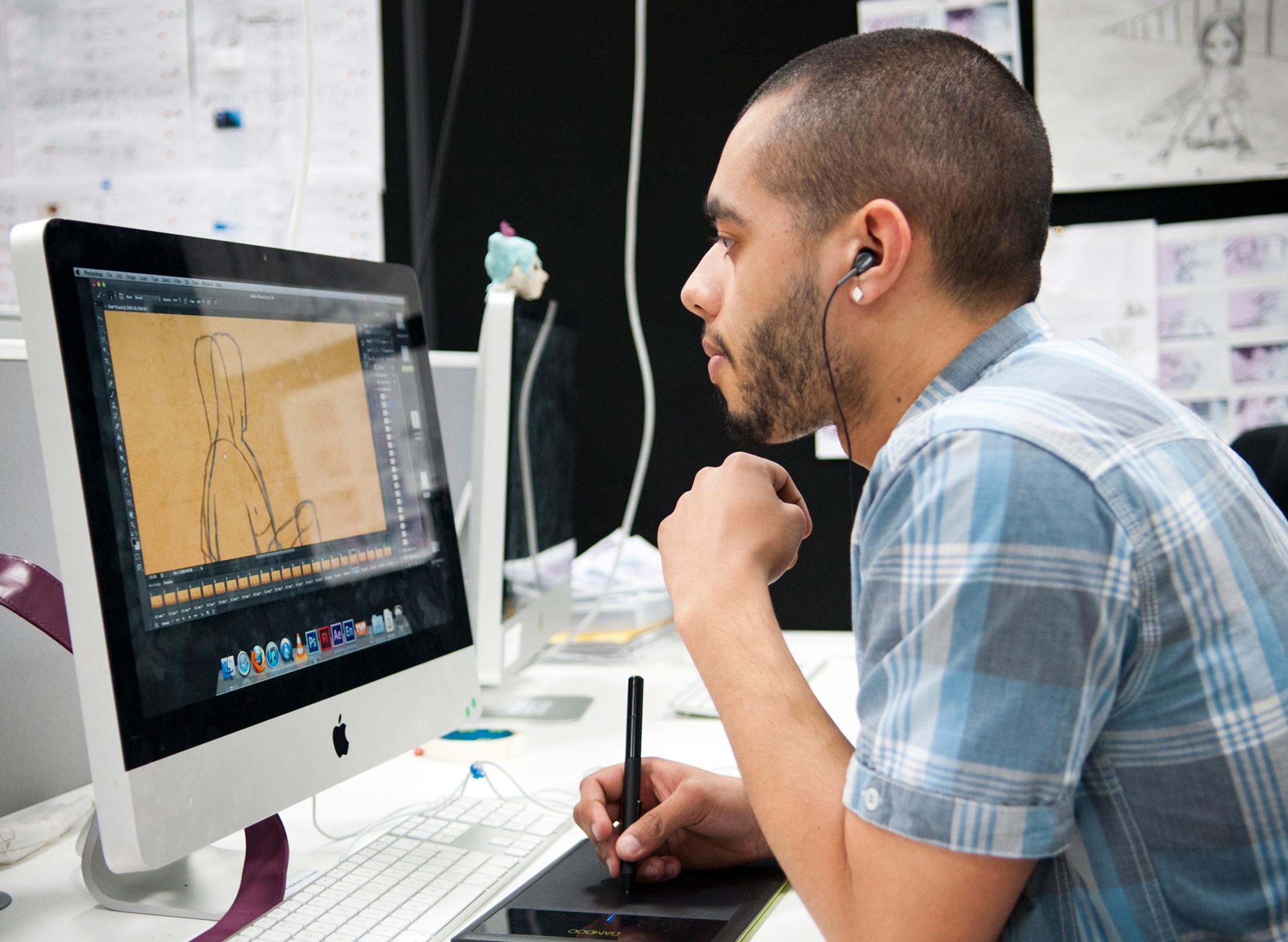 A student working on an animation project with an Apple Mac and stylus