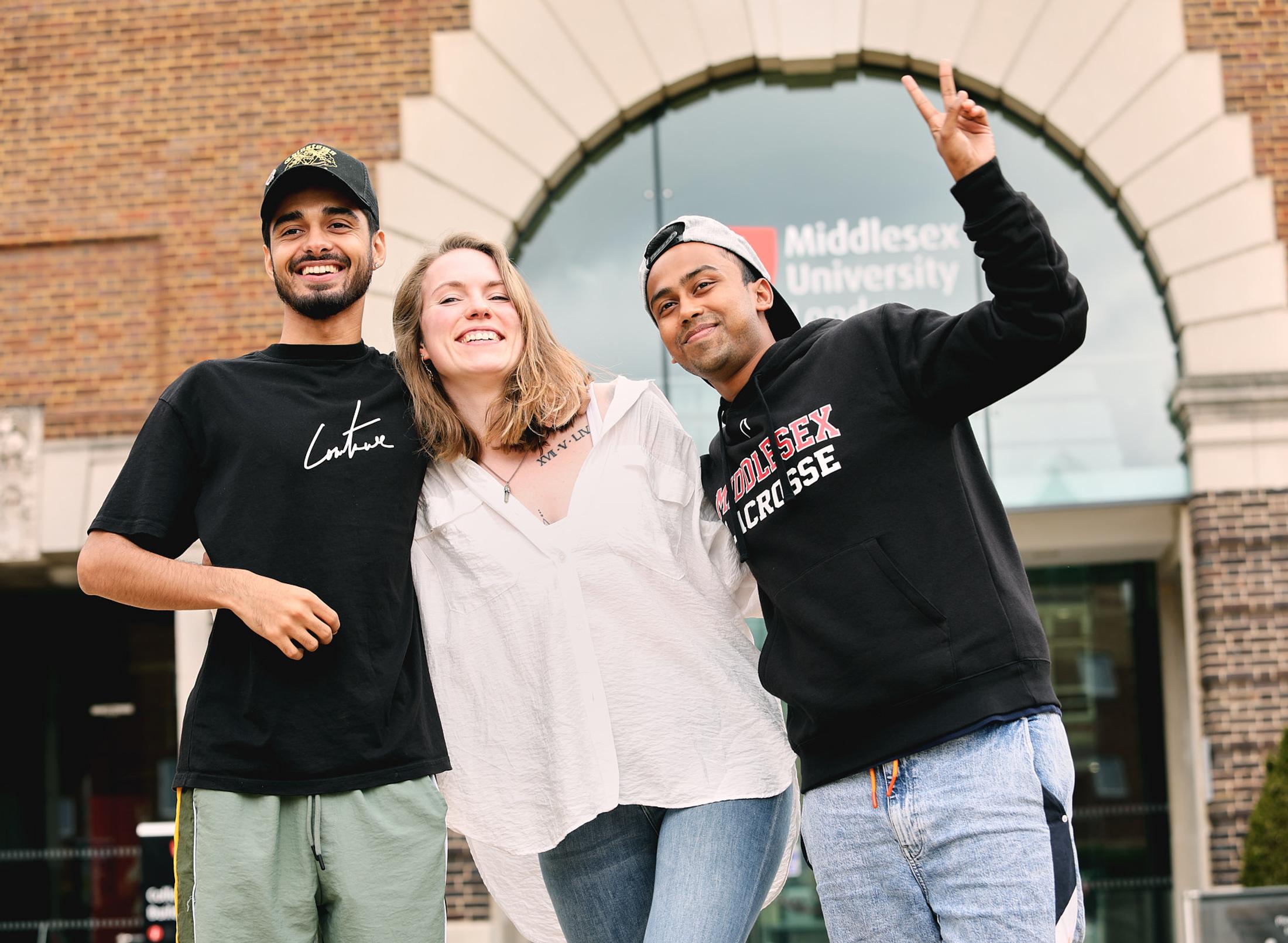 Three students stood together outside on campus