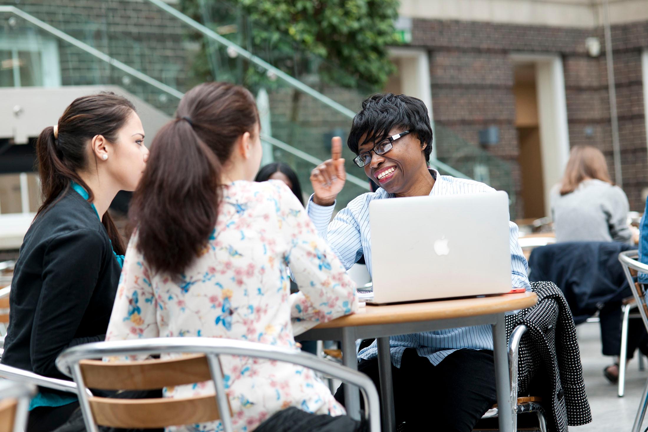 Three Middlesex University students sitting at a table in the quad